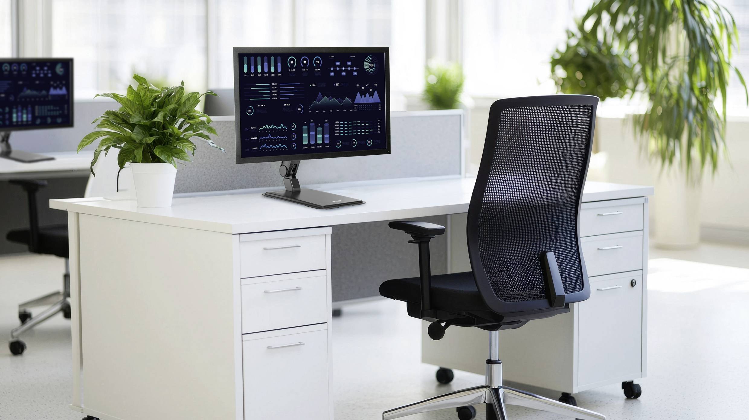 Modernes Büro mit zwei Schreibtischen, auf denen jeweils ein Computer mit Leistungsgrafiken steht. Ein Bürostuhl und Topfpflanzen ergänzen die Einrichtung.