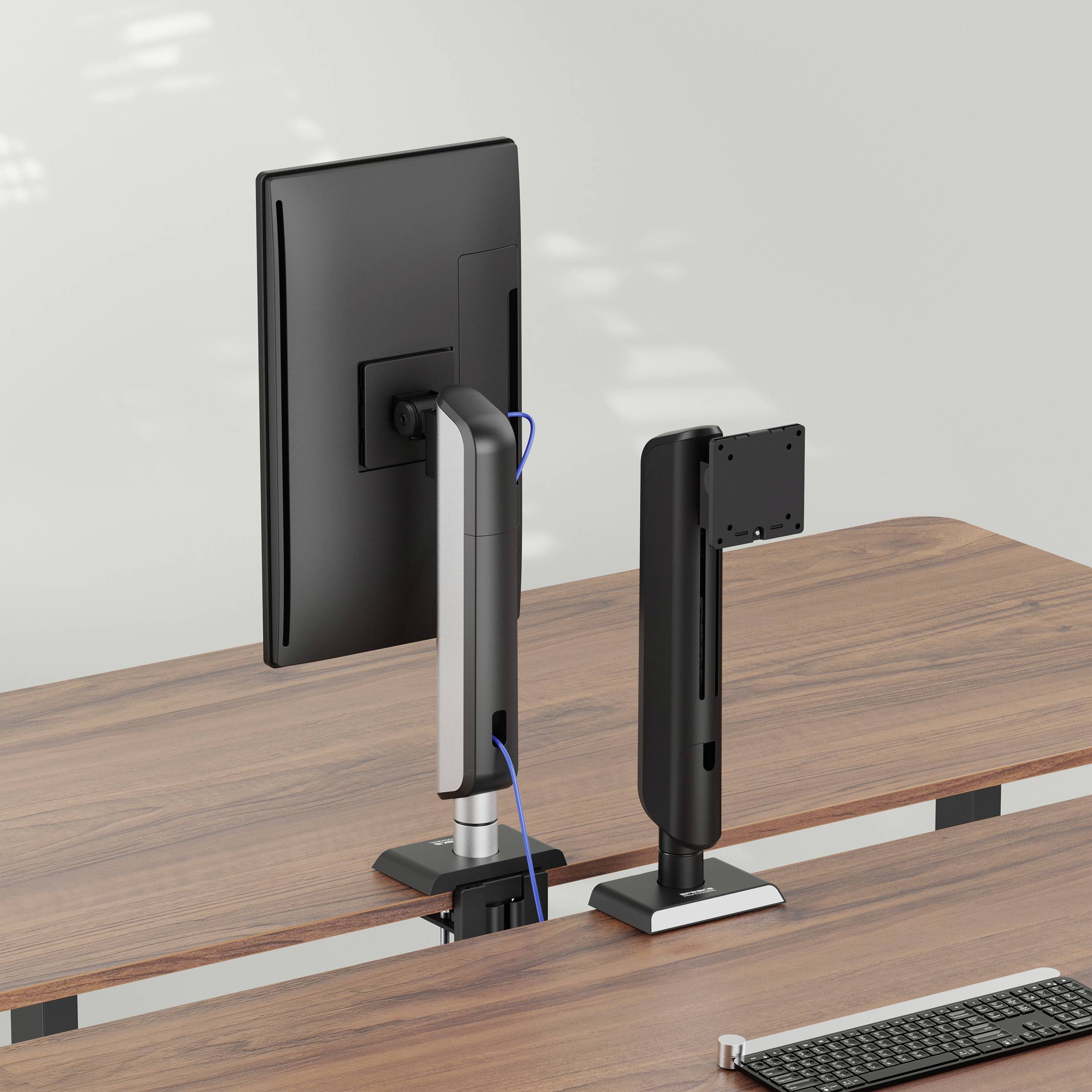 Zwei Computermonitore mit Ständerhalterungen sind nebeneinander auf einem Holzschreibtisch positioniert, von hinten betrachtet.