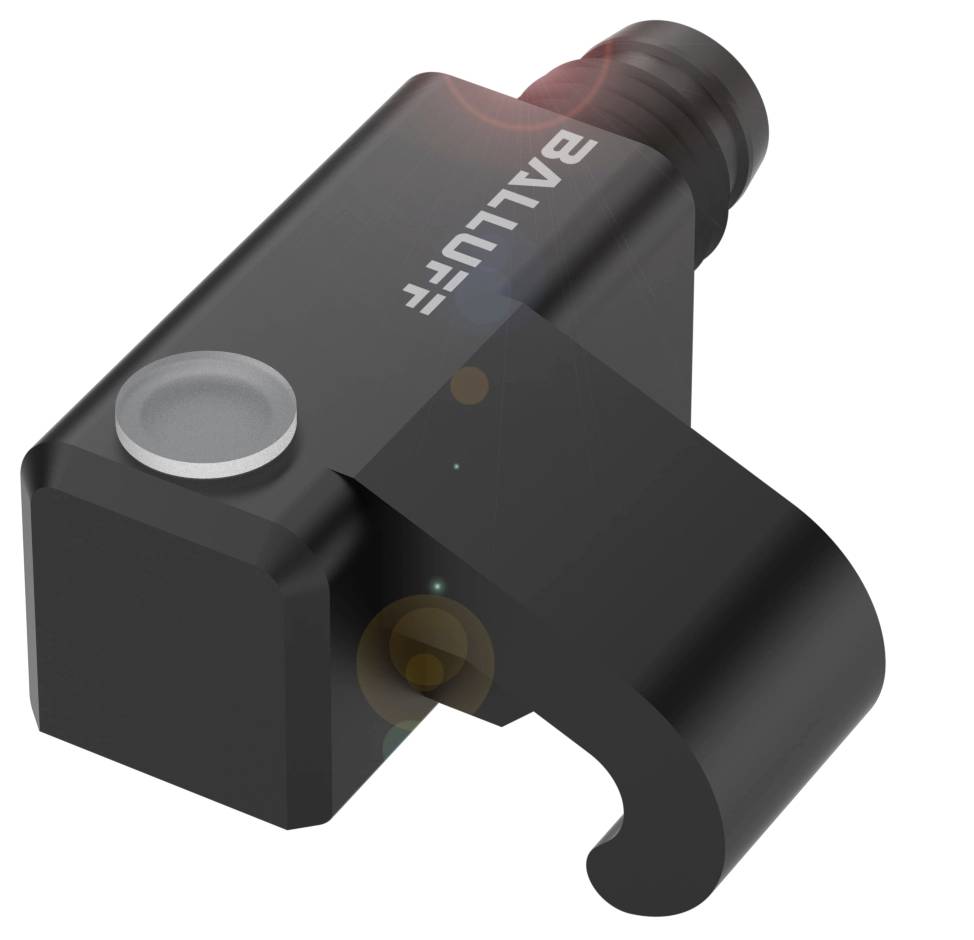 Ein schwarzes, rechteckiges Kunststoffteil mit einem Haken und der Aufschrift 'BALLUFF'. Dient vermutlich als Sensor oder Halterung.