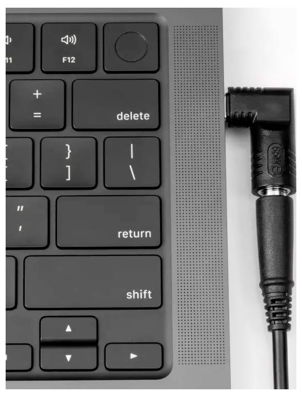 Schwarze Tastatur eines Laptops mit angeschlossenem Audiokabel auf der rechten Seite. Der Fokus liegt auf den Tasten und dem Kabel.