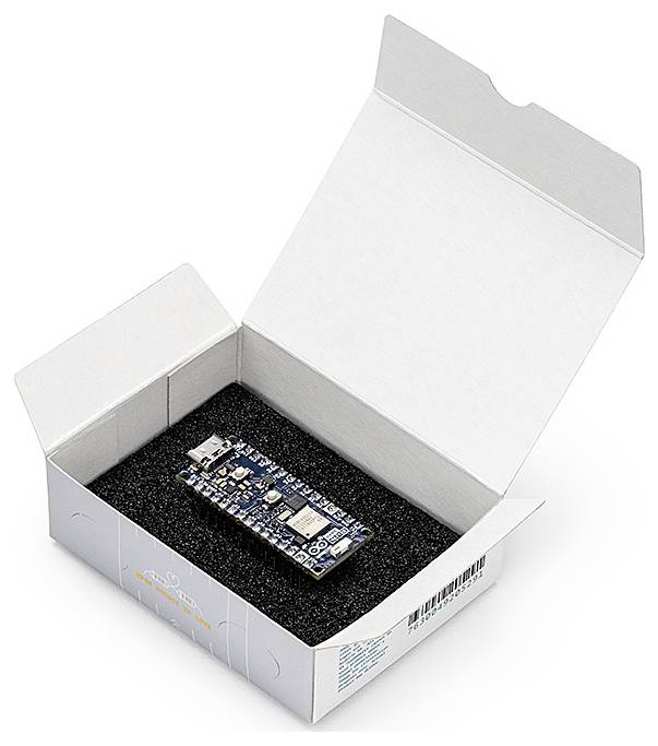 Ein elektronisches Mikrocontroller-Board liegt in einer teilgeöffneten weißen Schachtel auf schwarzem Schaumstoff padding.