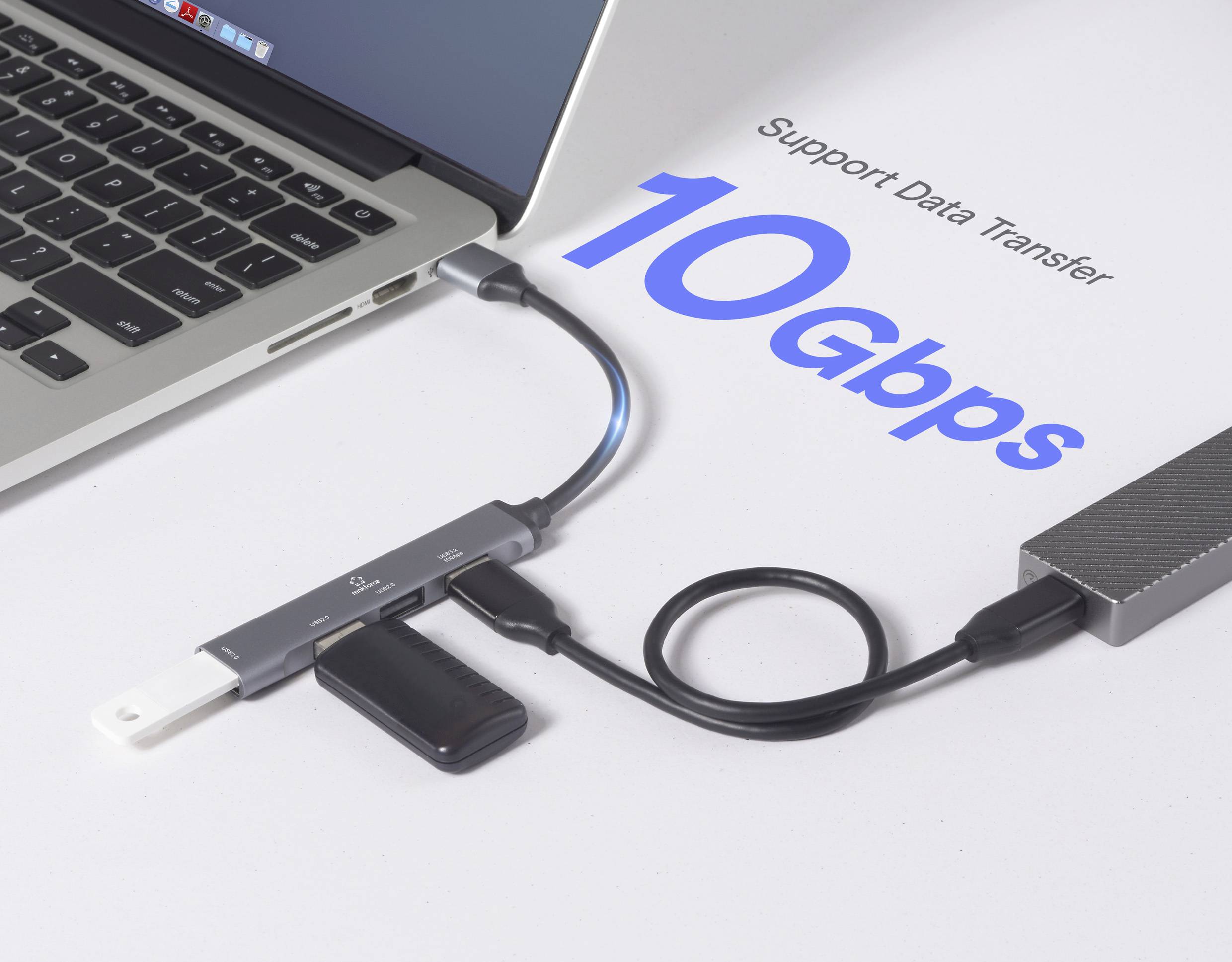 Ein Laptop, der an einen USB-Hub mit verschiedenen angeschlossenen Geräten angeschlossen ist und „Datenübertragung unterstützen 10 Gbps