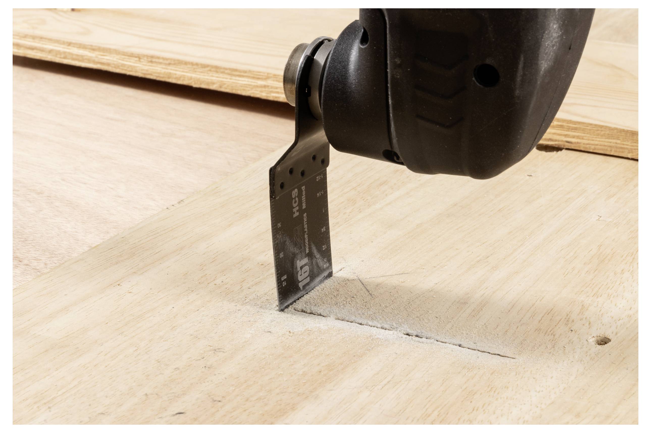 Ein Elektrowerkzeug mit einer Schneidklinge wird gezeigt, während es in eine Holzoberfläche schneidet. Die Klinge hat Messmarkierungen für Präzision.