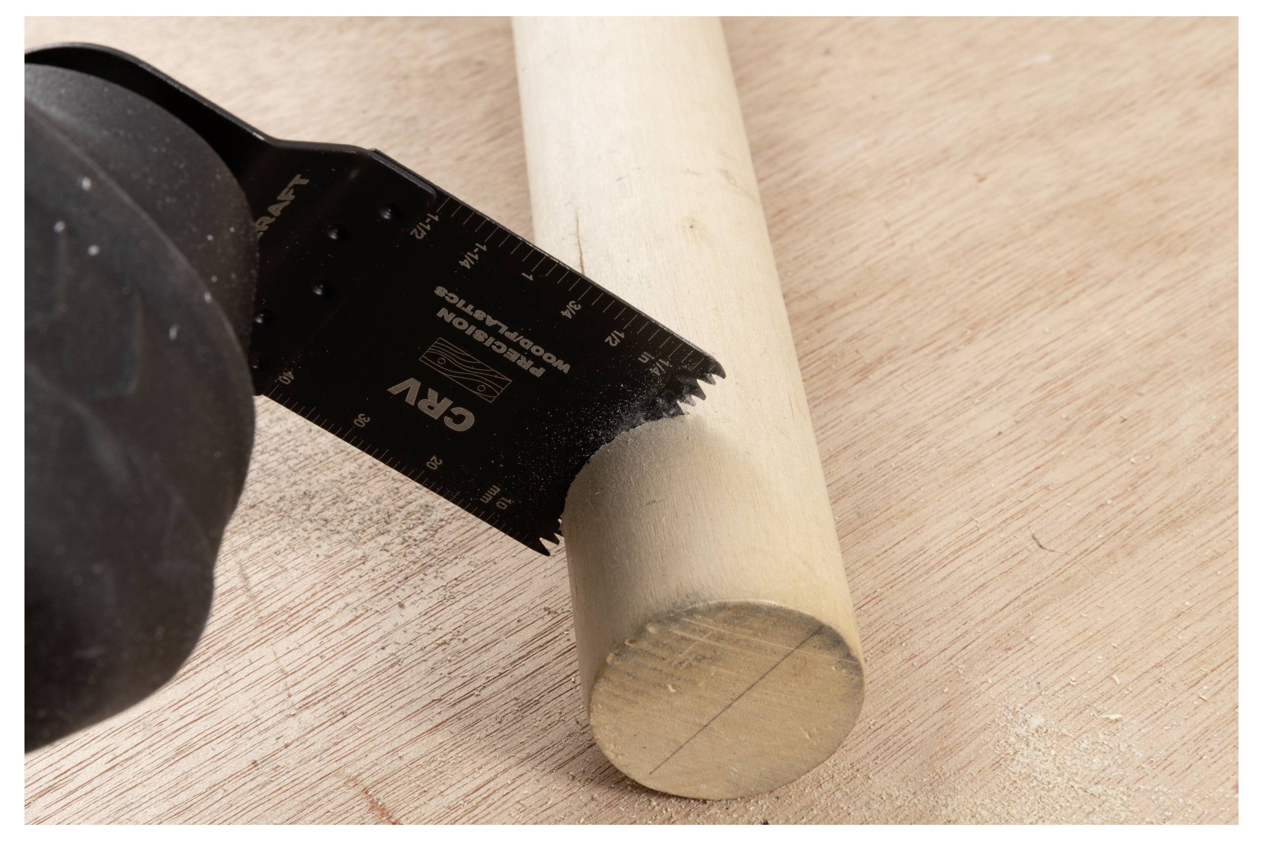 Eine Hand in einem schwarzen Handschuh verwendet eine Säge, um einen Holzdübel auf einer Sperrholzoberfläche zu sägen und zeigt eine Nahaufnahme des Sägevorgangs.