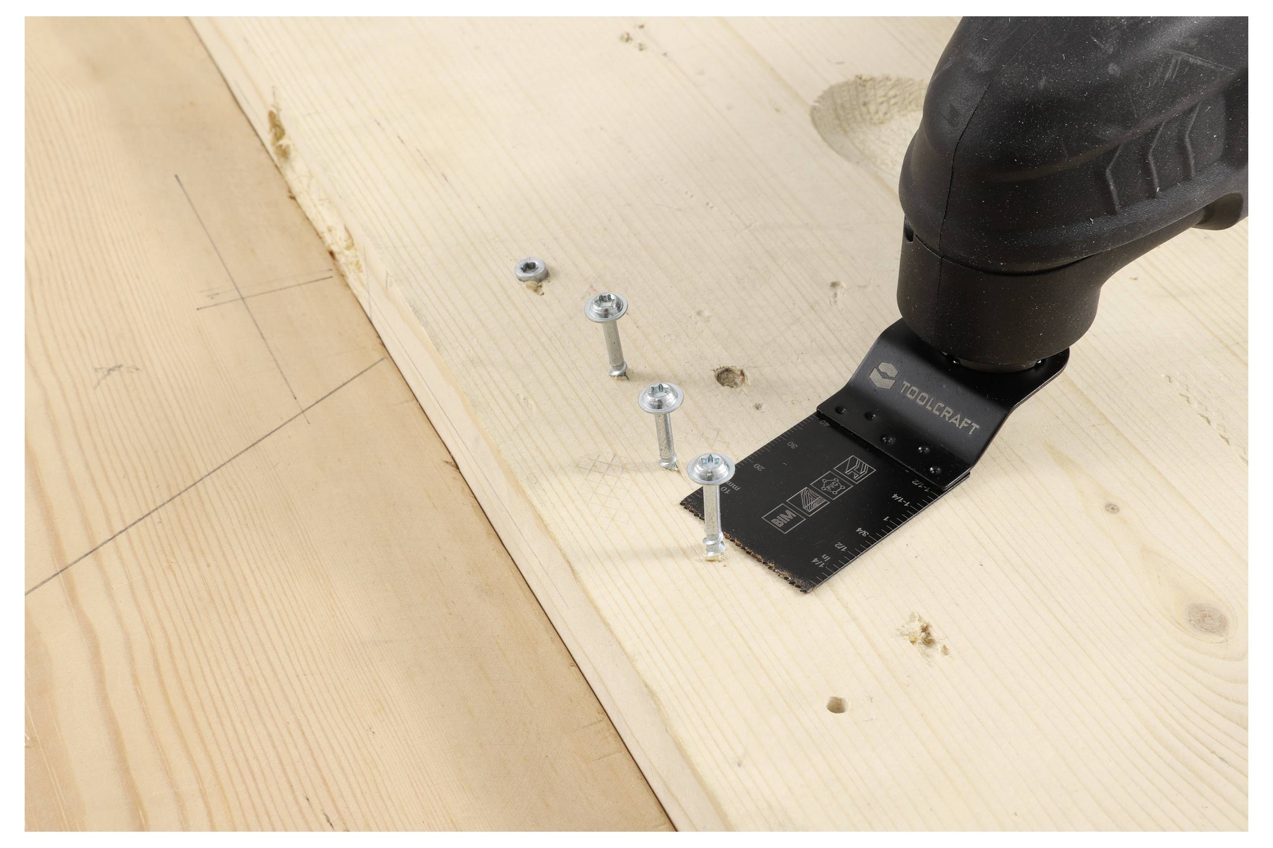 Eine Elektrowerkzeug mit einer Schneidklinge ist in der Nähe von Schrauben auf einem Holzbrett positioniert. Der Aufbau deutet auf eine Vorbereitung zum Schneiden oder Bauen hin.