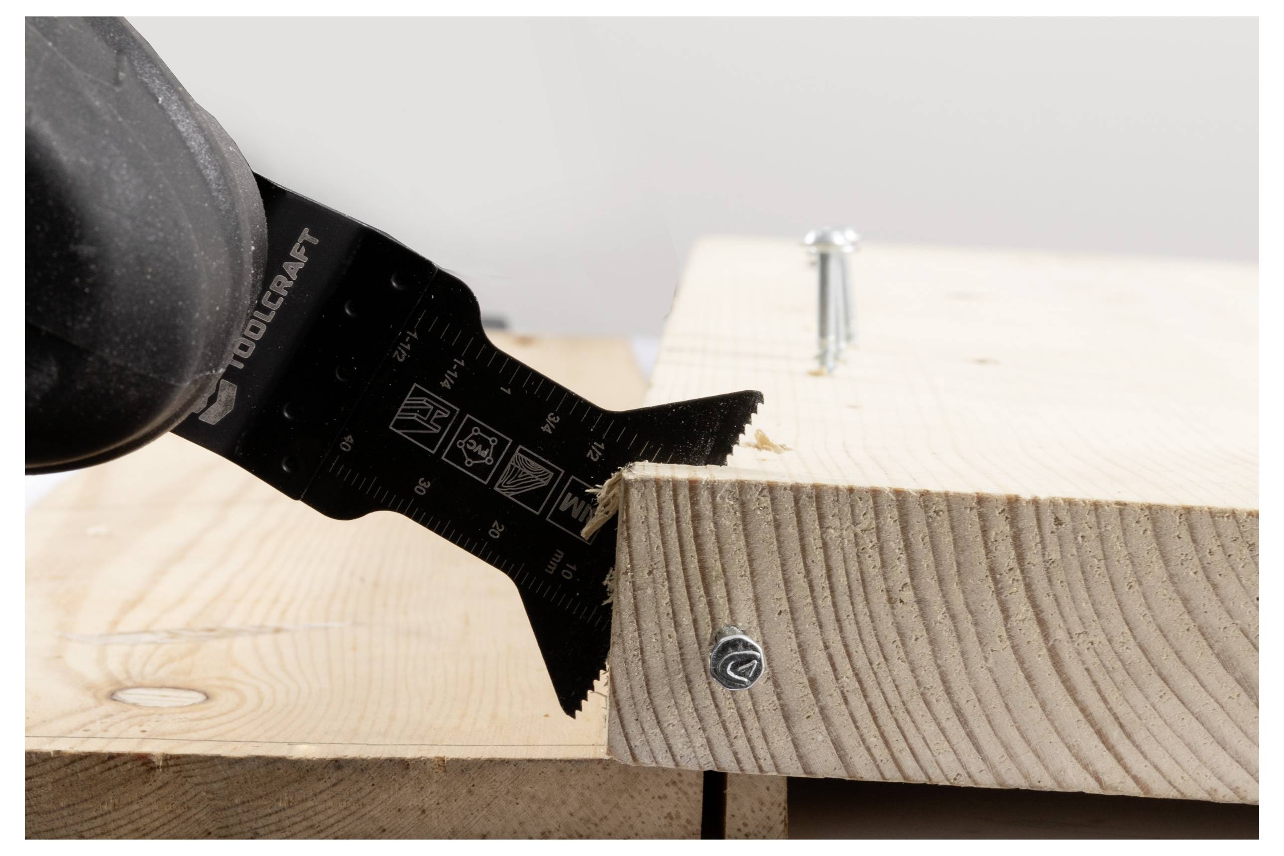 Eine Sägeblatt, das durch eine mit Schrauben befestigte Holzplanke schneidet und dabei Holzbearbeitungshandlung und Präzision zeigt.