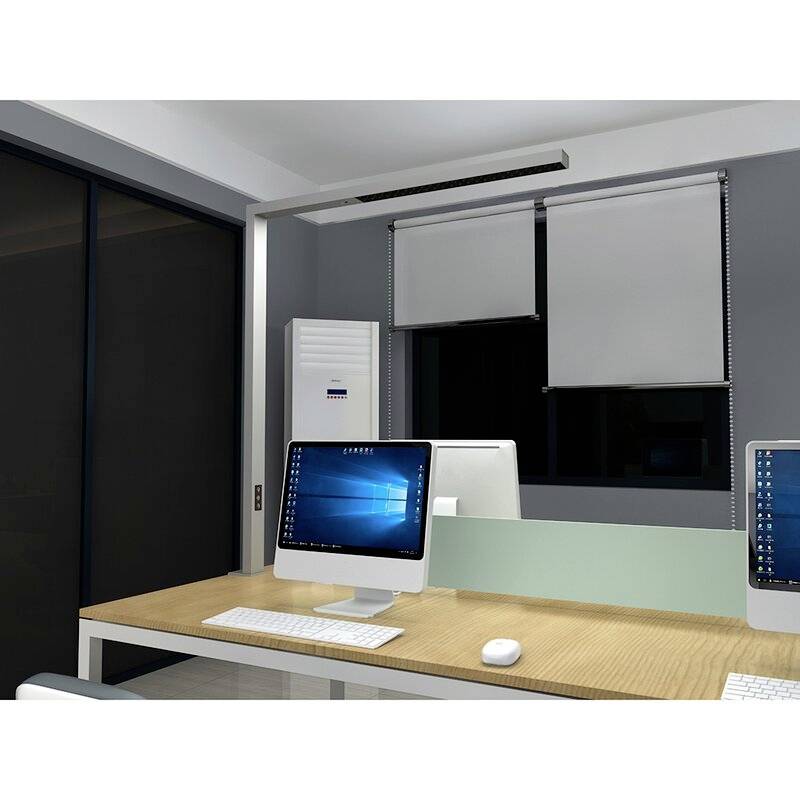 Ein moderner Büroraum mit zwei weißen Computern auf einem Holztisch. Im Hintergrund befinden sich geschlossene Jalousien vor Fenstern.