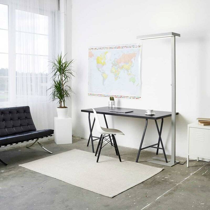 Ein modernes Büro mit Schreibtisch, Stuhl, Stehlampe und Weltkarte an der Wand. Sitzbank und Pflanze am Fenster.