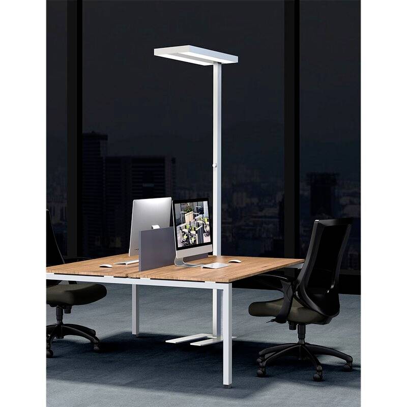 Ein moderner Büroraum mit zwei ergonomischen Bürostühlen an einem Tisch mit Computern und einer schlanken Stehlampe.