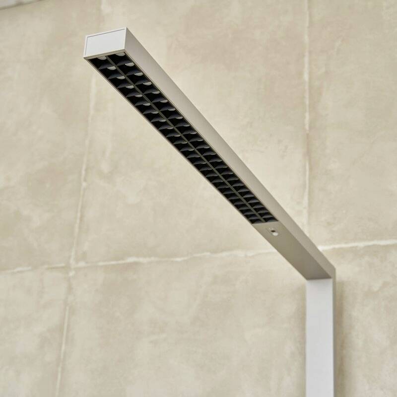 Ein modernes, minimalistisches LED-Licht mit schwarzem Gitterdesign, montiert an einer beigen Wand.