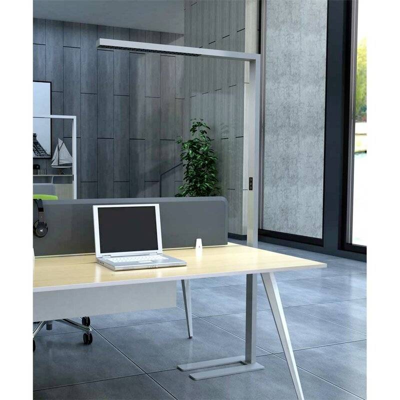 Moderner Büroraum mit großem Schreibtisch, Laptop, Trennwand, Lampe und Pflanze im Hintergrund. Sitzbereich mit grauem Boden und Fenster.