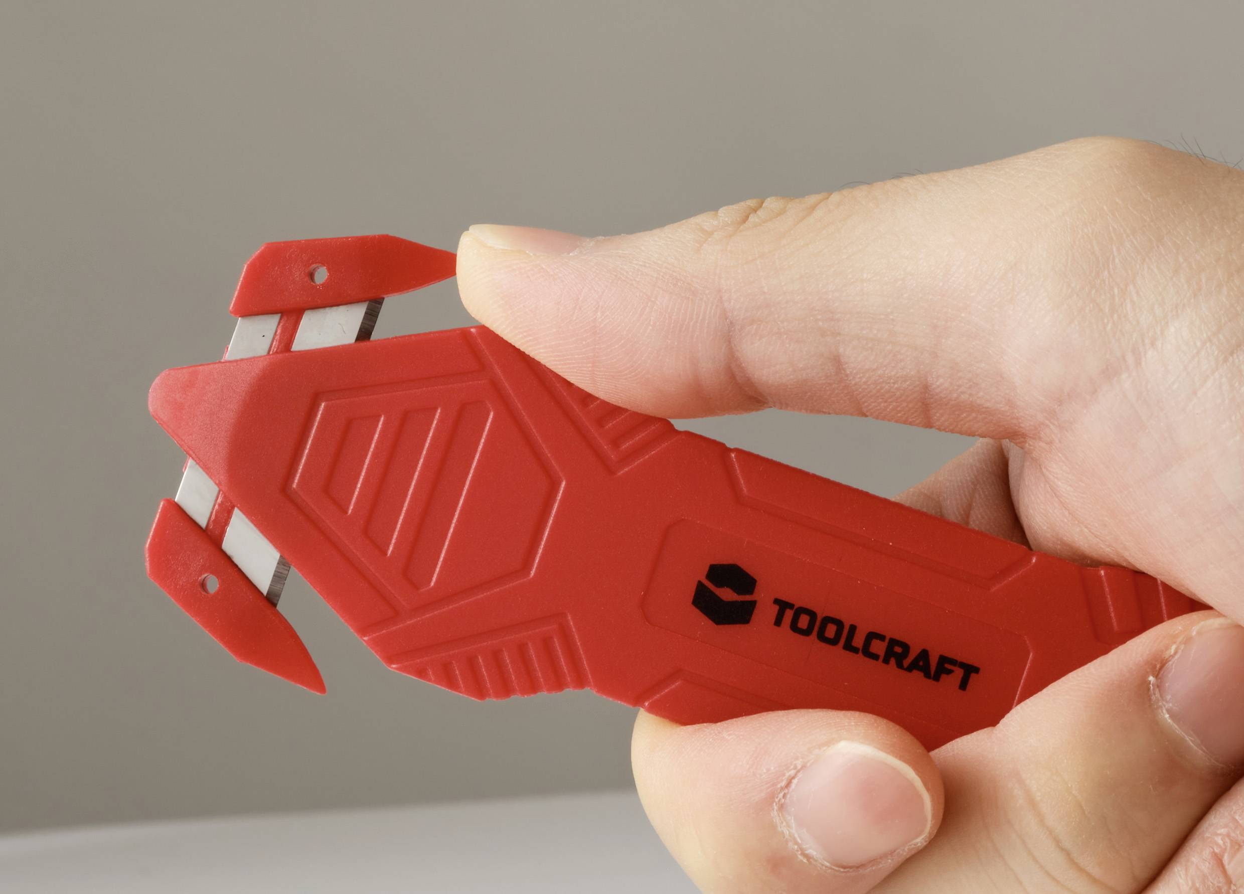 Eine Hand, die ein rotes Werkzeug mit der Aufschrift 