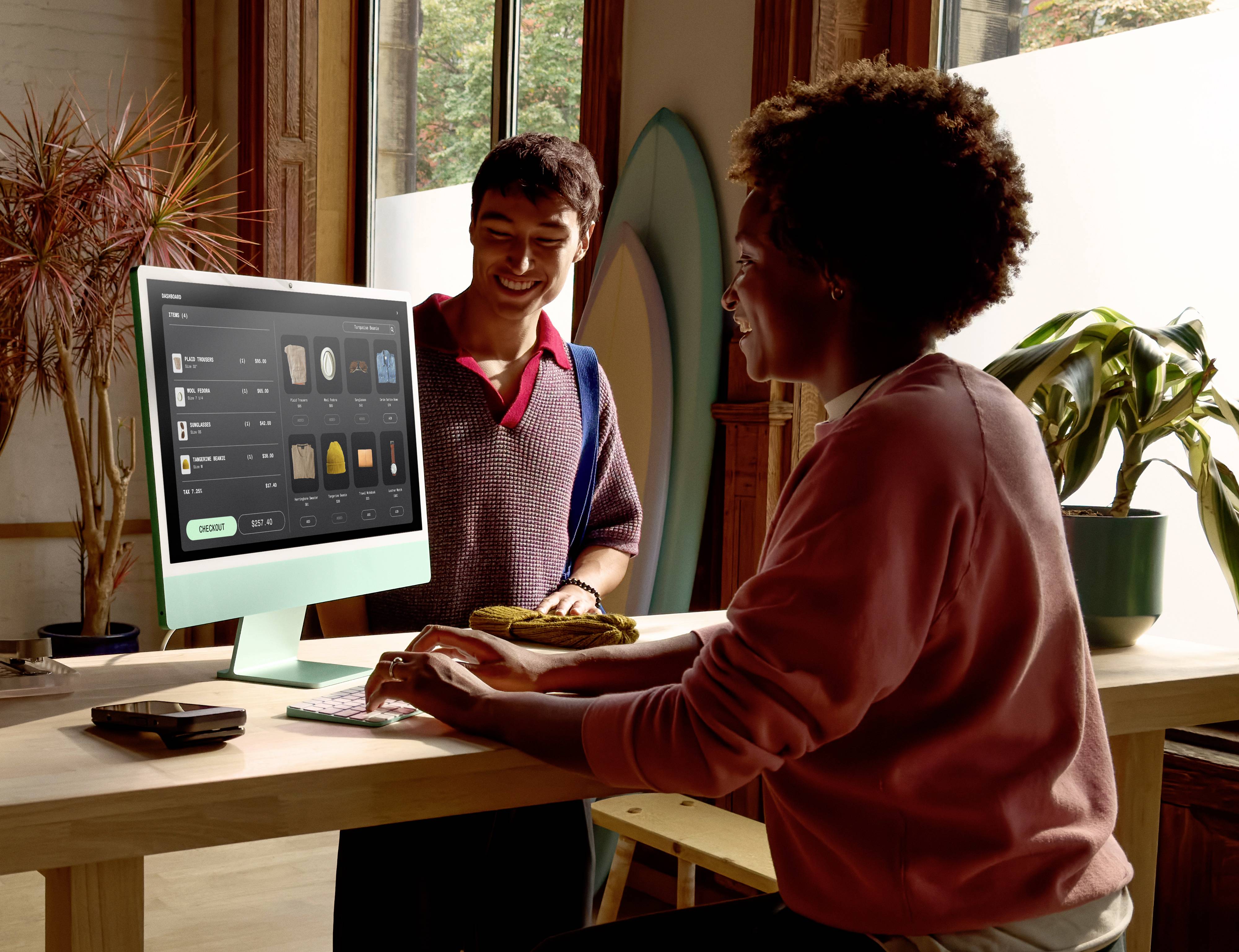 Zwei Personen in einem modernen Büroumfeld, die an einem Desktop-Computer sitzen, wobei eine 'Einkaufstasche'-Anwendung auf dem Bildschirm gezeigt wird.