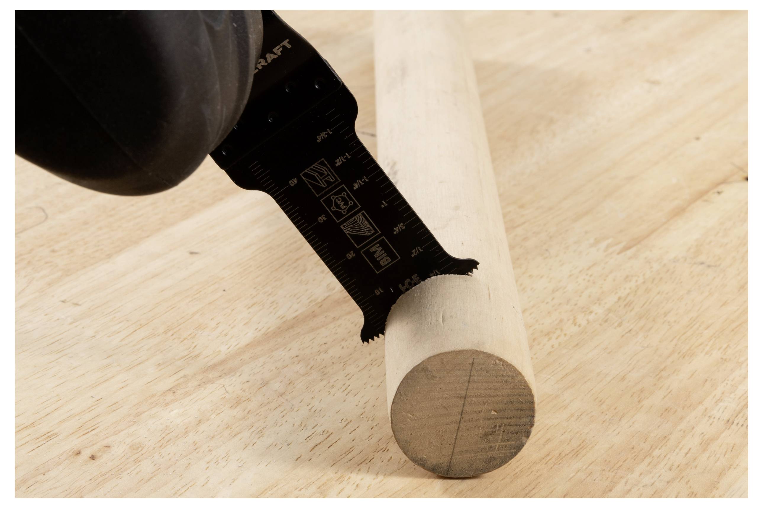 Eine Elektrowerkzeugklinge, die einen Holzdübel auf einer hellen Holzoberfläche schneidet.