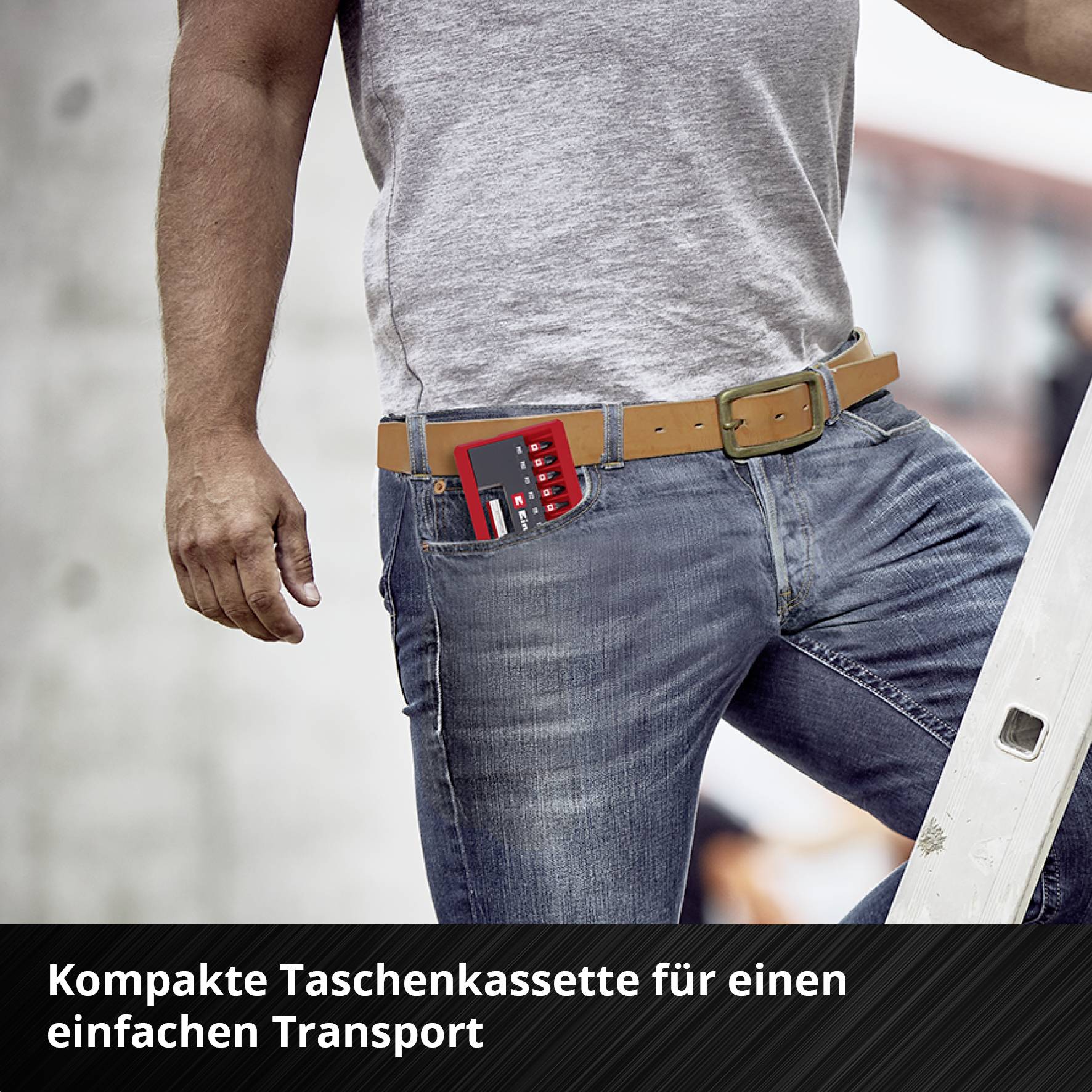 Ein Mann in Jeans steckt eine kompakte, schwarze Taschen-Kassette mit roten Details in seine Vordertasche für einfachen Transport.