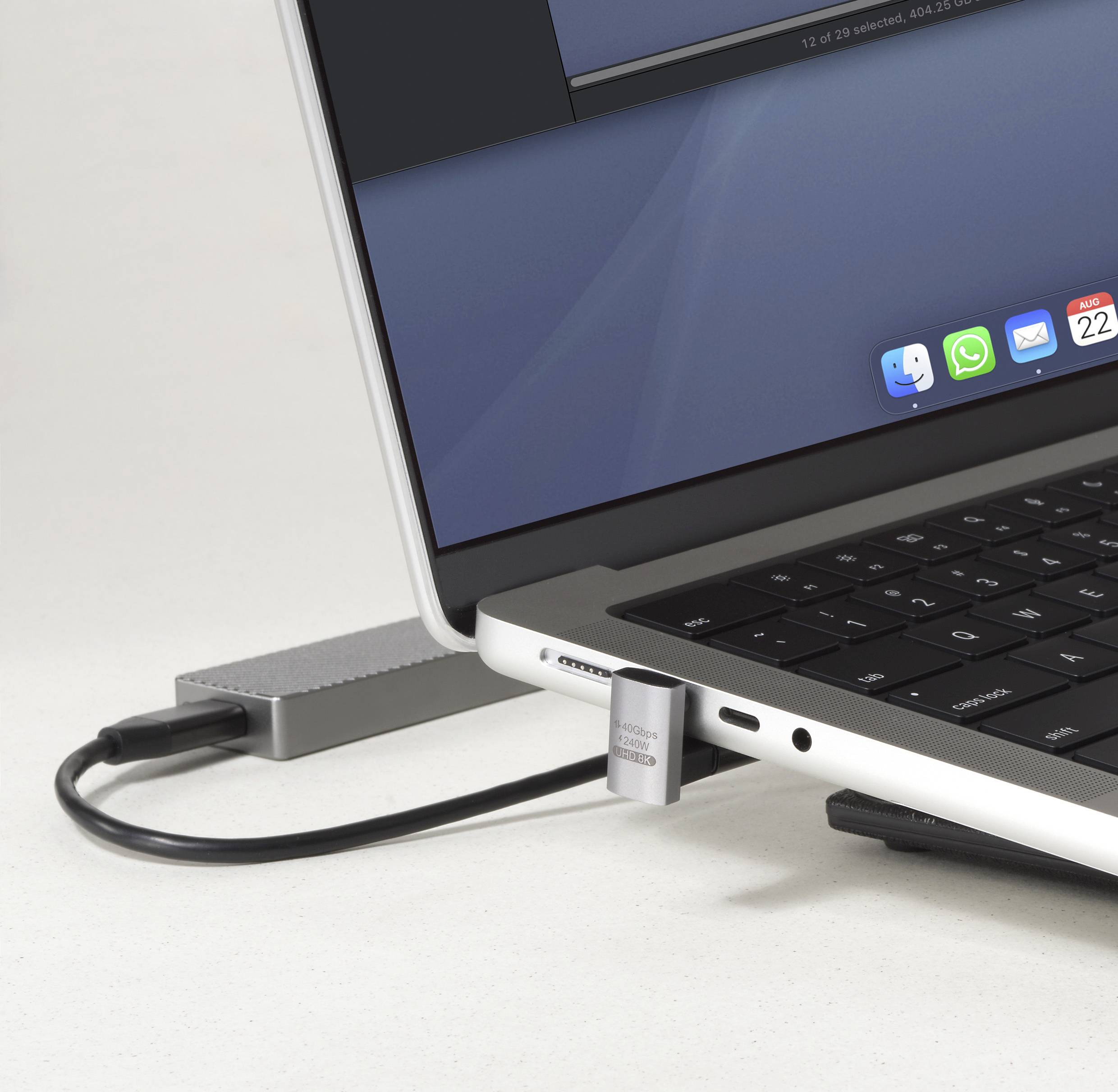 Eine Nahaufnahme der Seite eines Laptops, die verschiedene Anschlüsse und einen eingesteckten USB-Stick zeigt. Ein unscharfer Bildschirm zeigt mehrere Anwendungssymbole.