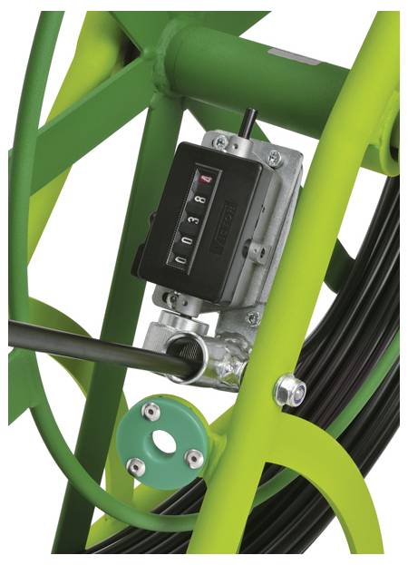 Eine Nahaufnahme einer Kabeltrommel mit einem mechanischen Zähler, der Zahlen anzeigt und auf einem grünen Gestell montiert ist, der die Länge des Kabels misst.
