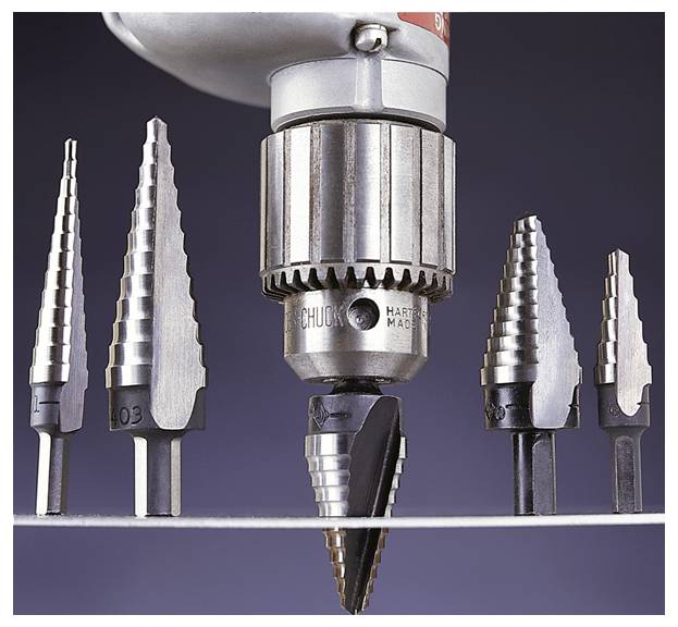 Eine Bohrmaschine mit einem Stufenbohrer bestückt ist über verschiedenen Stufenbohrern positioniert. Der Hintergrund ist eine einfarbige dunkle Oberfläche.