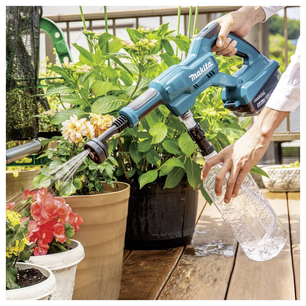 Eine Person verwendet ein blaues Makita-Handgerät zum Gießen von Topfblumen auf einer Holzterrasse, mit verschiedenen Pflanzen im Hintergrund.