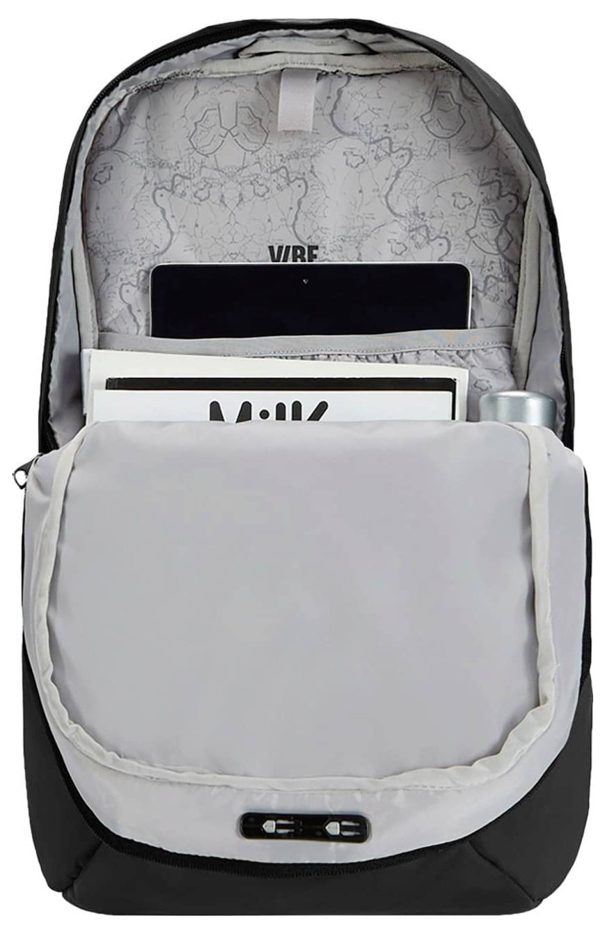 Ein offener Rucksack, der einen Innenraum mit Fächern zeigt, in denen ein Tablet, eine Zeitschrift und ein zylindrisches Objekt untergebracht sind, mit einem Muster im Inneren.