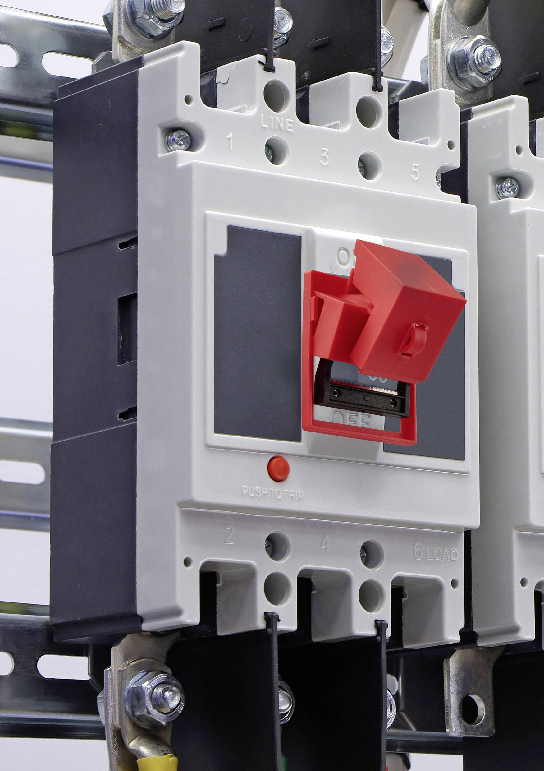 Ein grauer und roter elektrischer Sicherungsautomat, der auf einer Metallschiene montiert ist, mit Schaltern und Anschlusspunkten, die mit 