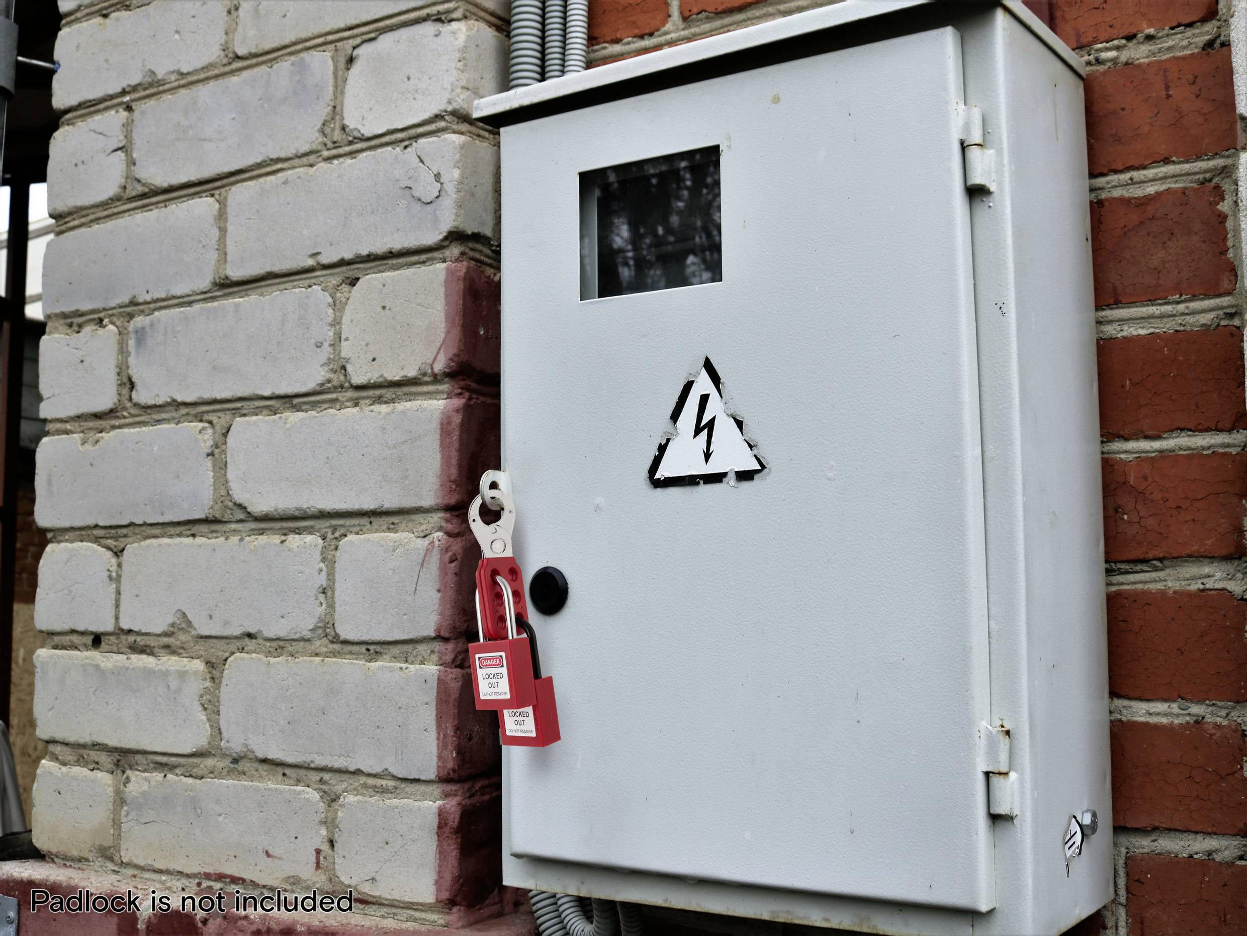 Elektrische Schalttafel, die an einer Ziegelwand montiert ist, mit einem Hochspannungs-Warnschild. Ein roter Sicherungsverschluss-Anhänger ist angebracht, der eingeschränkten Zugang anzeigt.