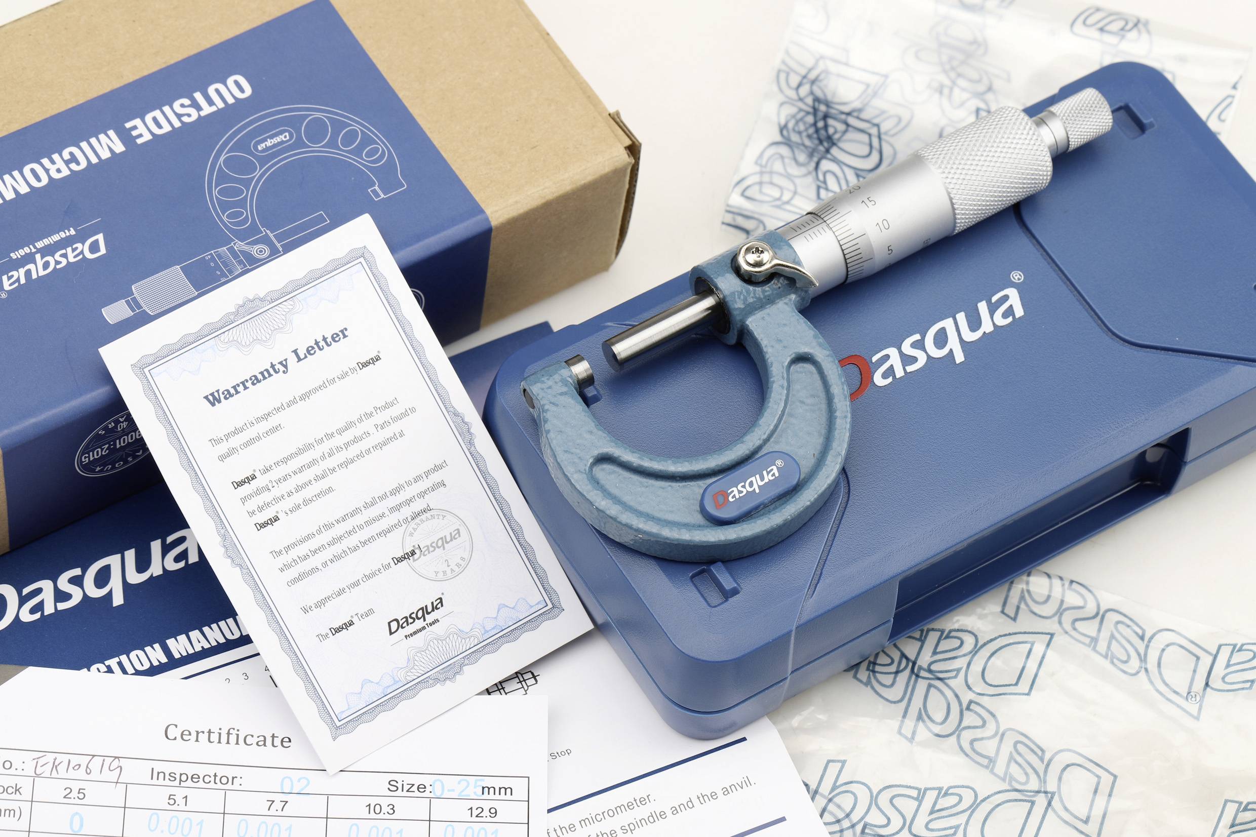 Blaues Mikrometer, Garantieschreiben und Zertifikate auf einem Tisch mit Dasqua-Verpackung.