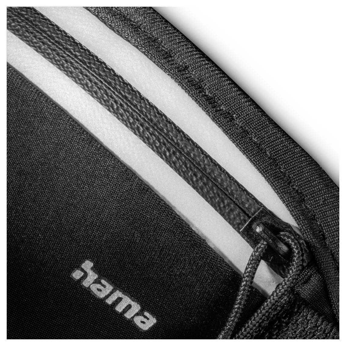 Nahaufnahme eines schwarzweißen Reißverschlusses auf einem Stoff mit dem Text 'hama'.