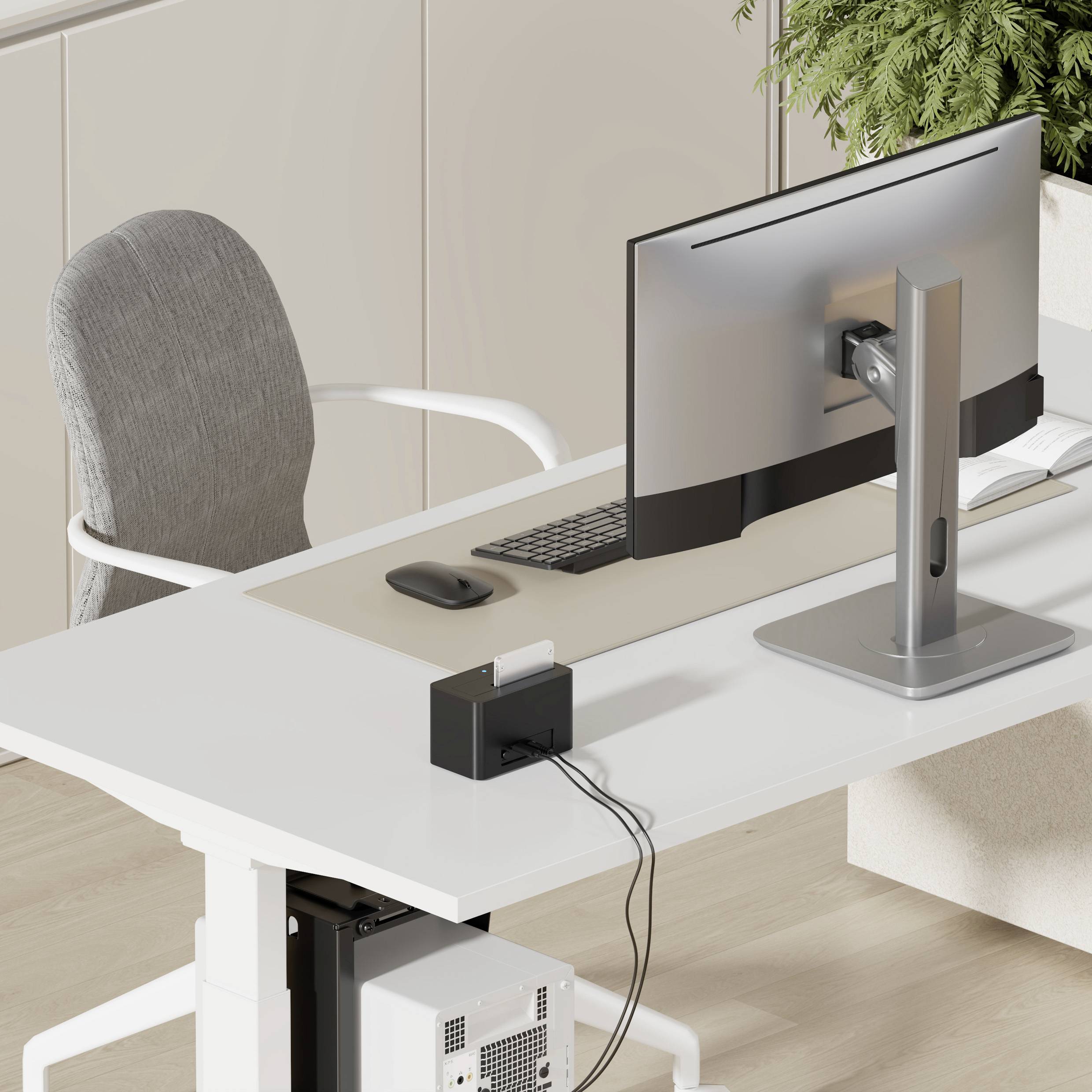 Ein modernes, minimalistisches Home Office mit einem großen Monitor auf einem weißen Schreibtisch, einem Stuhl und einer Topfpflanze in der Ecke.