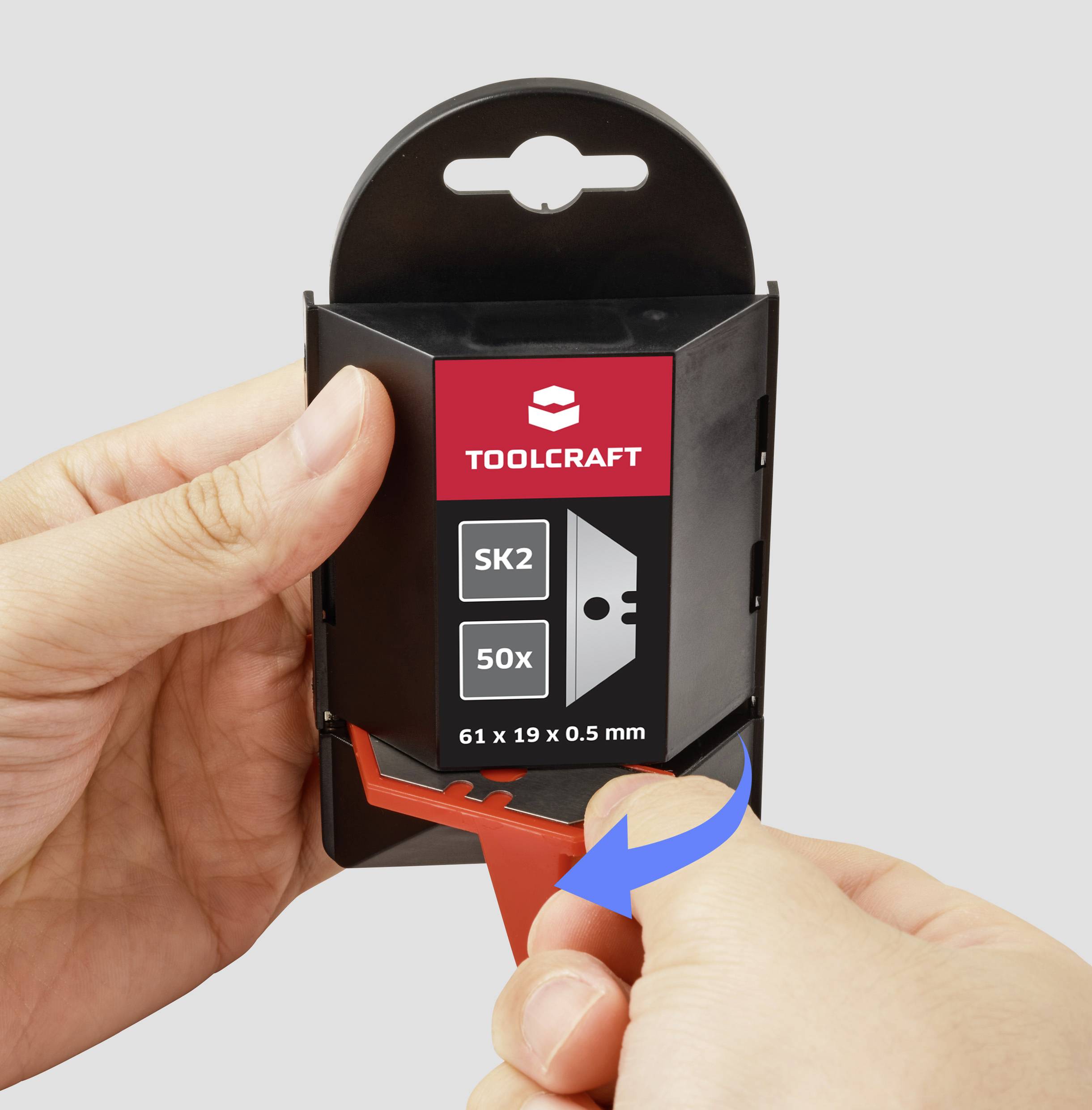 Hände öffnen eine schwarze 'TOOLCRAFT' Klingenverpackung mit 'SK2', '50x' und '61 x 19 x 0,5 mm' auf dem Etikett; eine rote Packung wird herausgezogen.