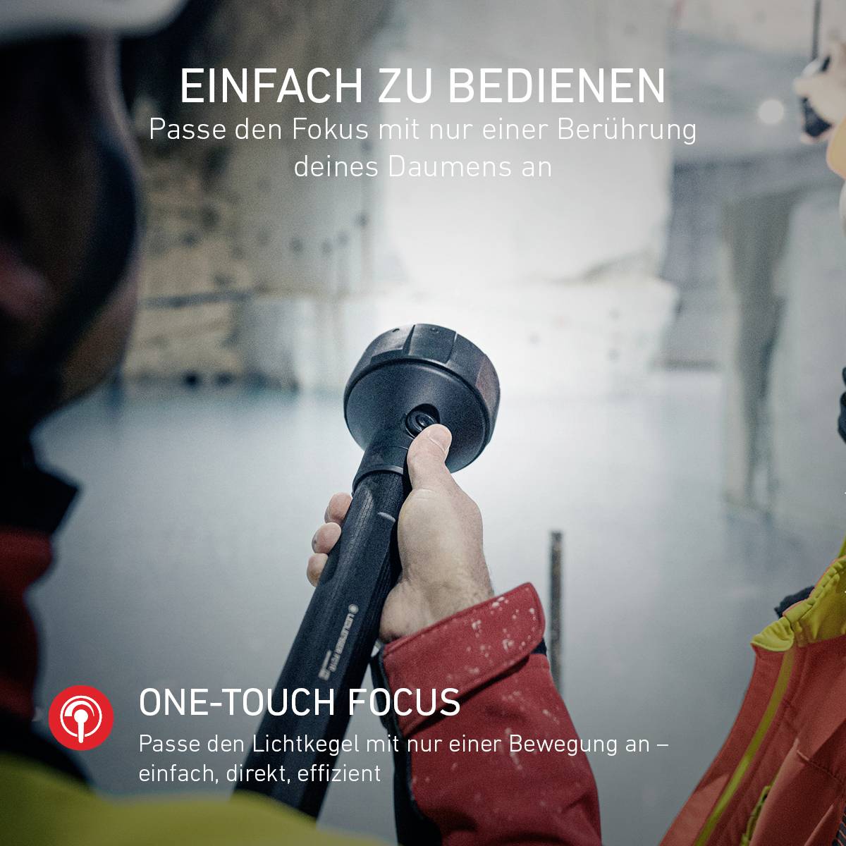 Person hält ein Kameraobjektiv. Text: Einfach zu bedienen, One-Touch Focus - Passe den Lichtkegel mit nur einer Bewegung an.