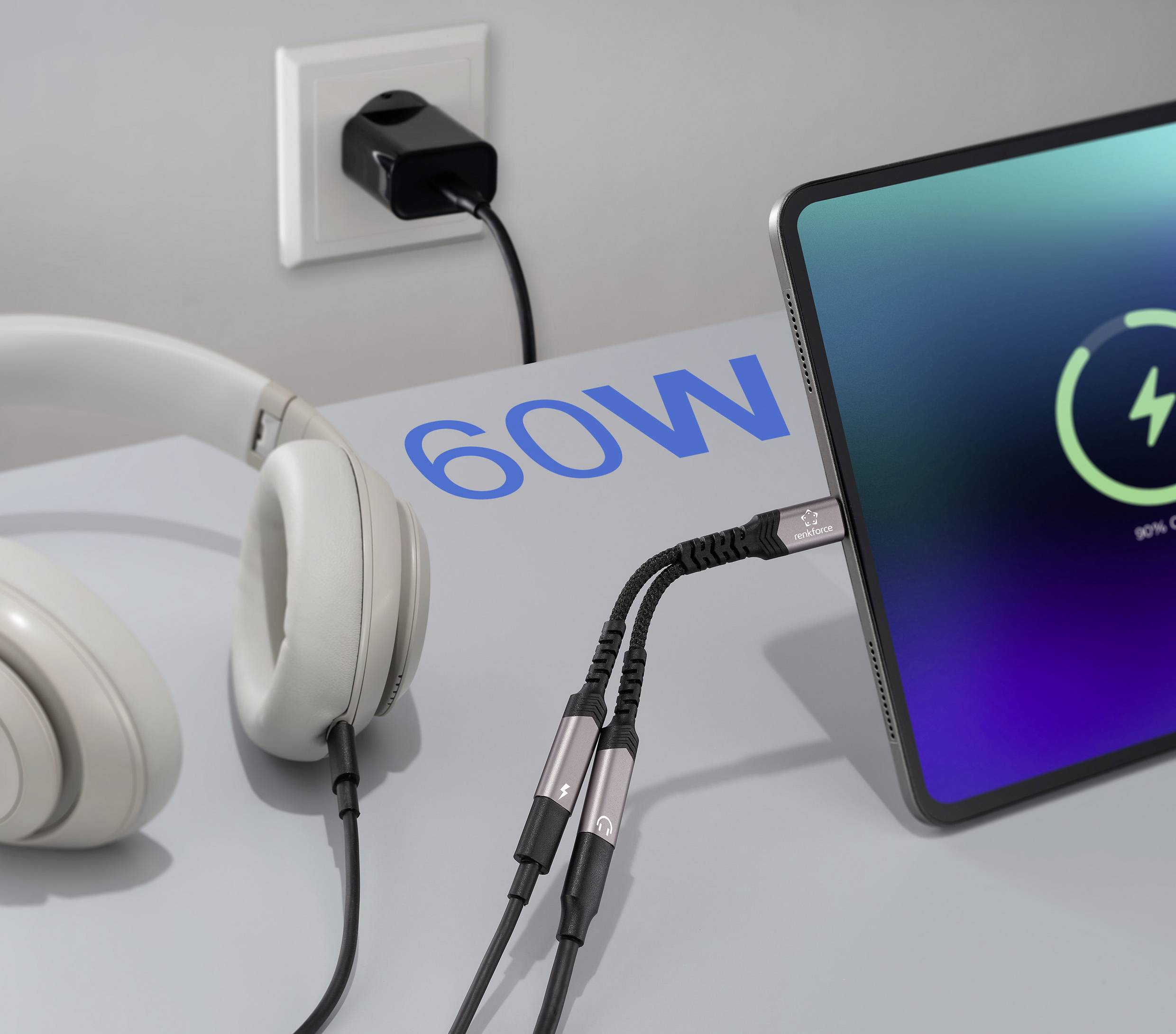 Ein Tablet lädt auf einem Schreibtisch neben Kopfhörern. Der Bildschirm zeigt ein Ladesymbol, und auf dem Schreibtisch steht '60W', was die Leistungsausgabe anzeigt.