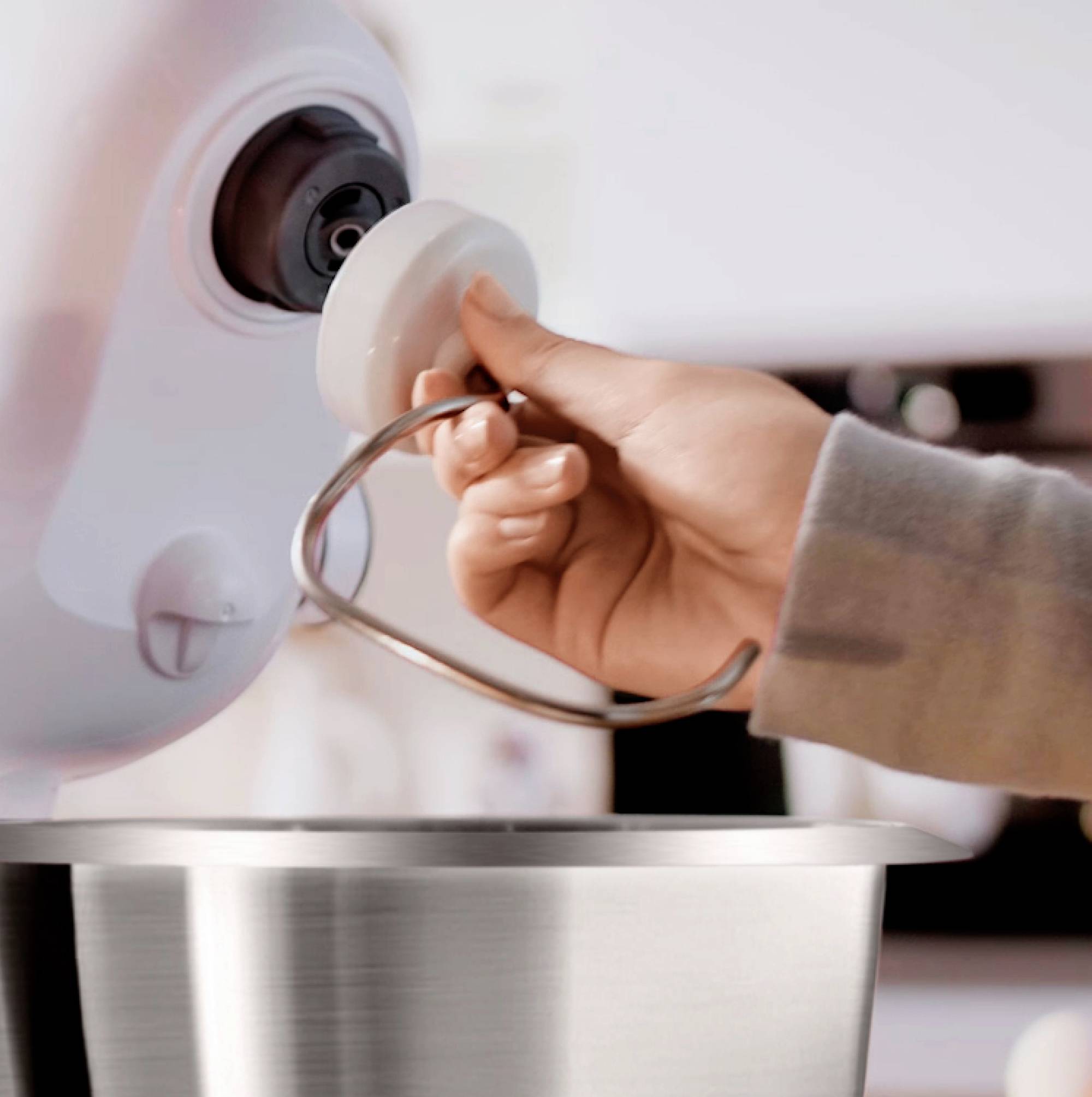 Eine Person befestigt einen Knethaken an einem Standmixer und bereitet ihn zur Verwendung vor.