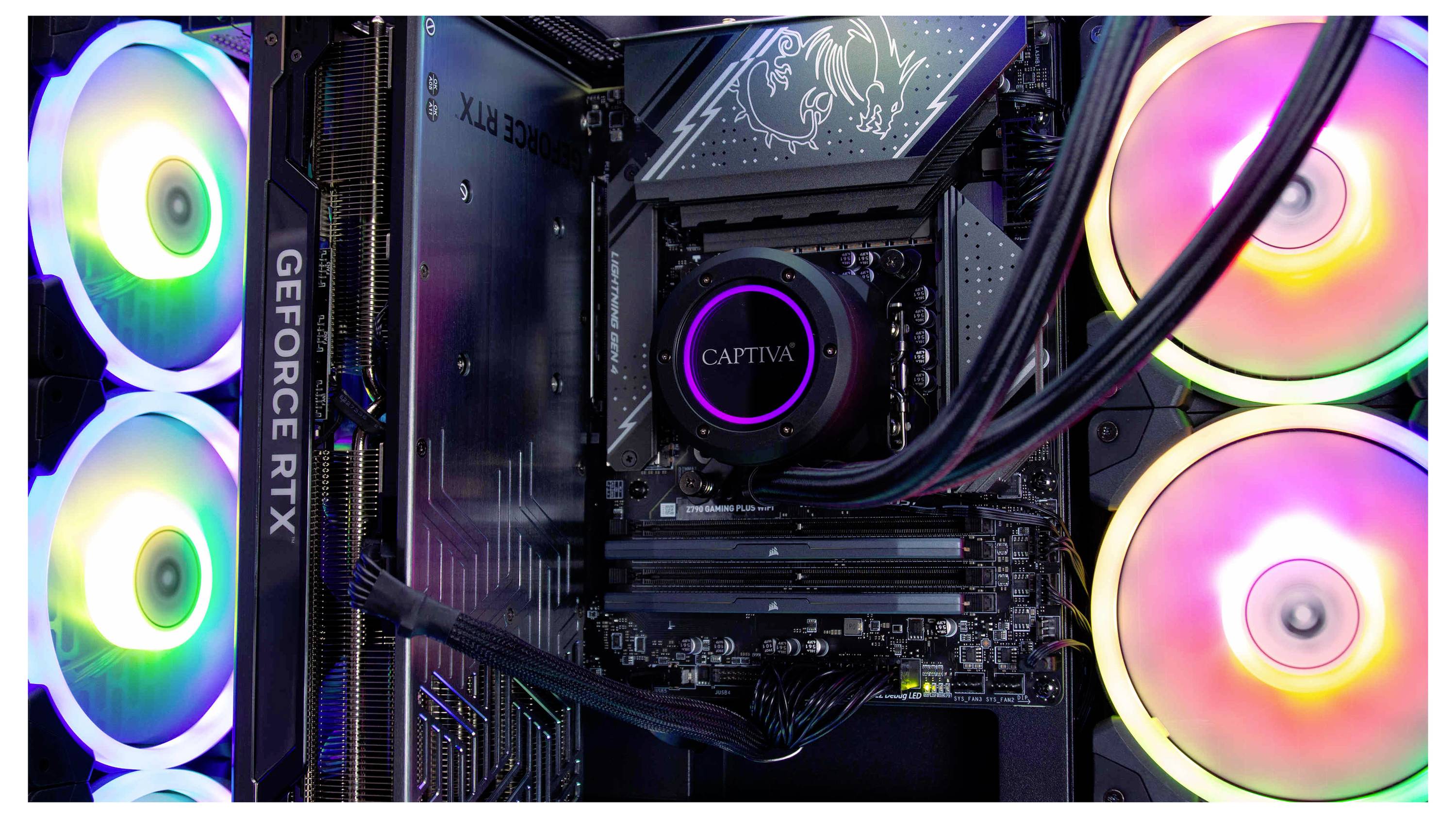Ein Gaming-Computer Innenraum mit mehrfarbigen LED-Lüftern. Eine GeForce RTX Grafikkarte und eine mit der Marke 'CAPTIVA' versehene Komponente sind zu sehen.