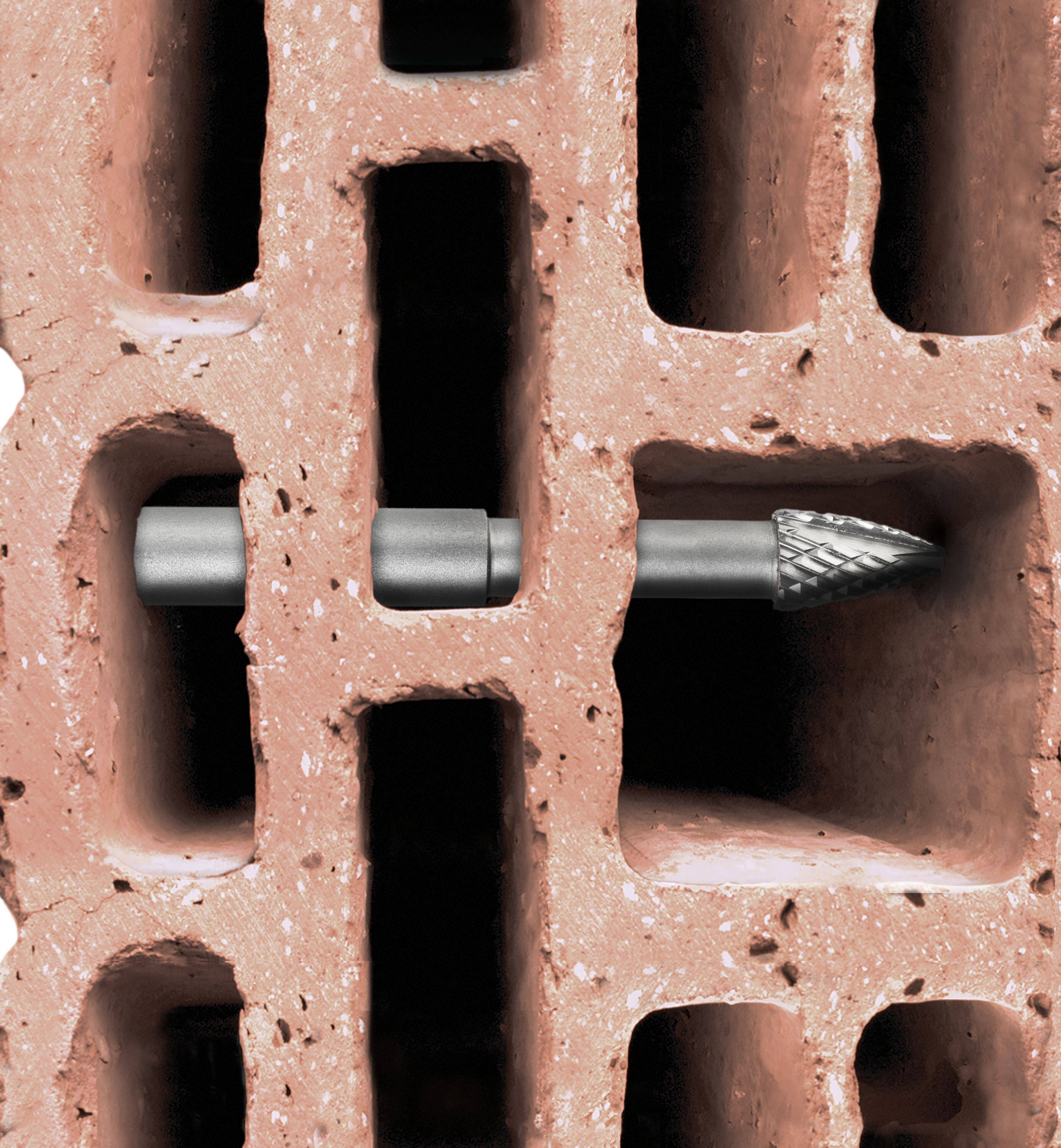 Ein Metallbohrer wird horizontal in einen hohlen Ziegelstein eingeführt und veranschaulicht das Konzept des Bohrens in Baumaterial.