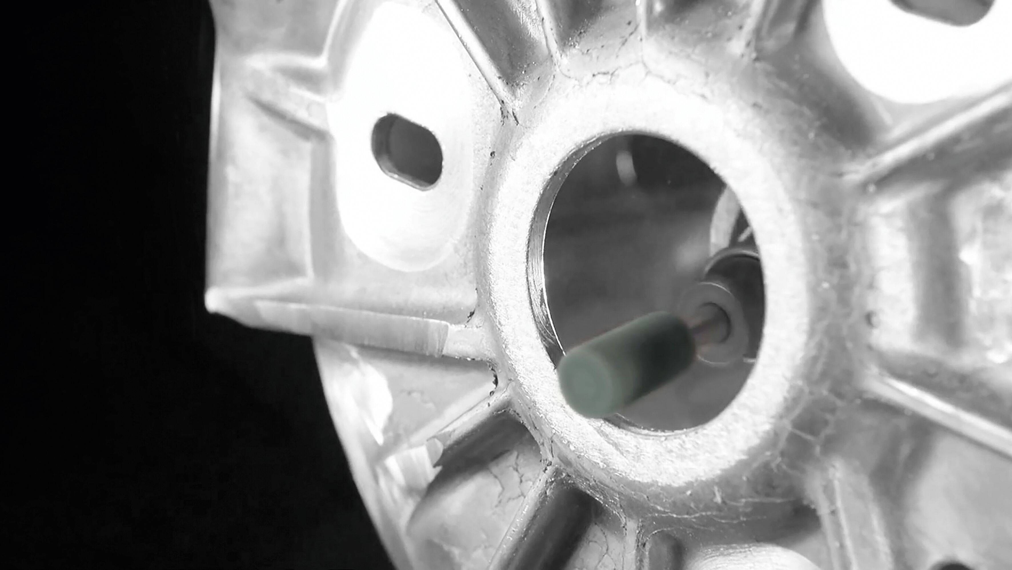 Eine Nahaufnahme eines kreisförmigen metallischen Mechanismus mit komplexen Designdetails, die seine zentrale Öffnung und radiale Muster hervorheben.