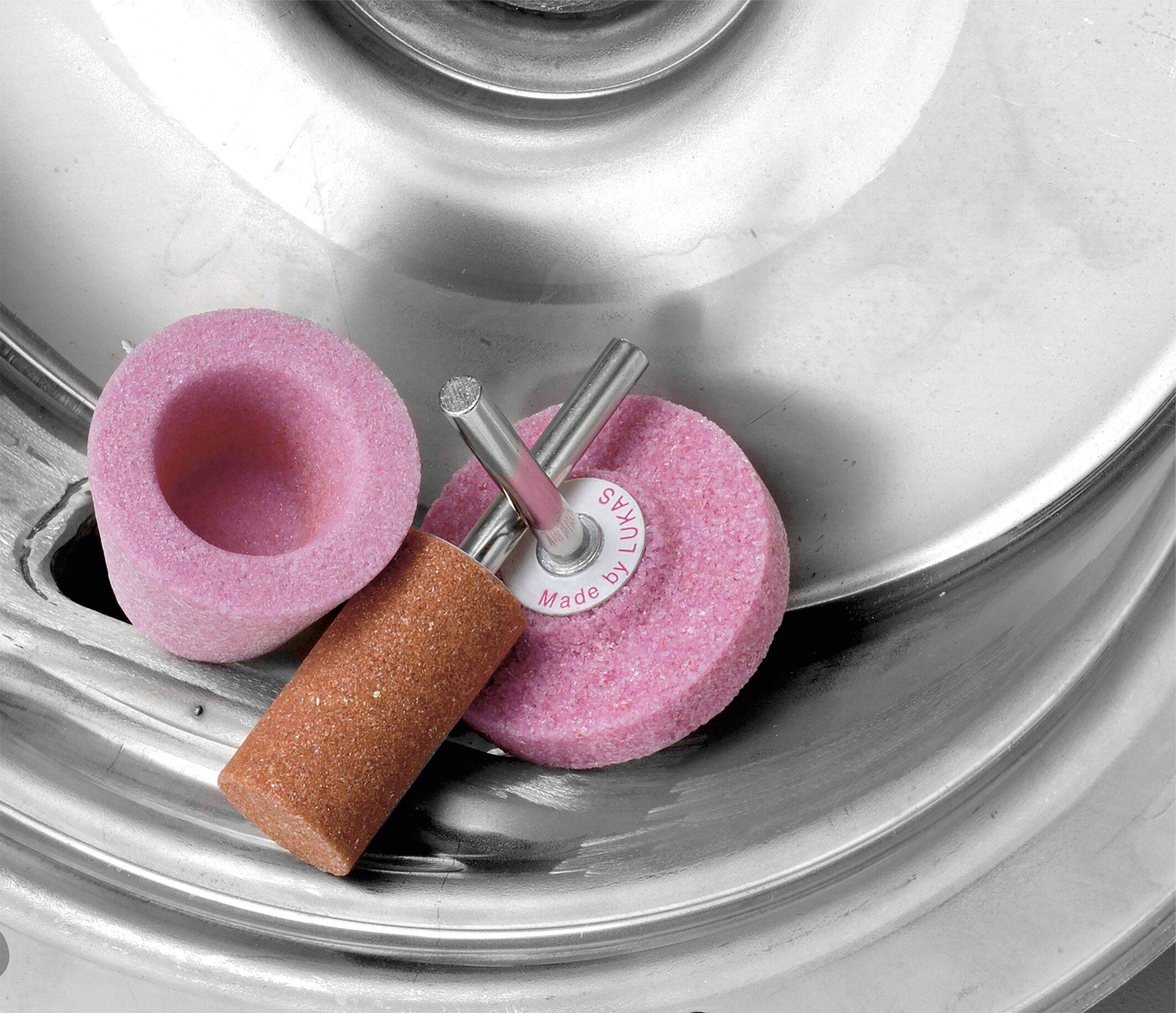 Schleifscheiben und Werkzeuge liegen auf einer Metalloberfläche. Sie werden für Formgebungs- und Oberflächenbearbeitungsaufgaben bei Bearbeitungs- oder Polierarbeiten verwendet.