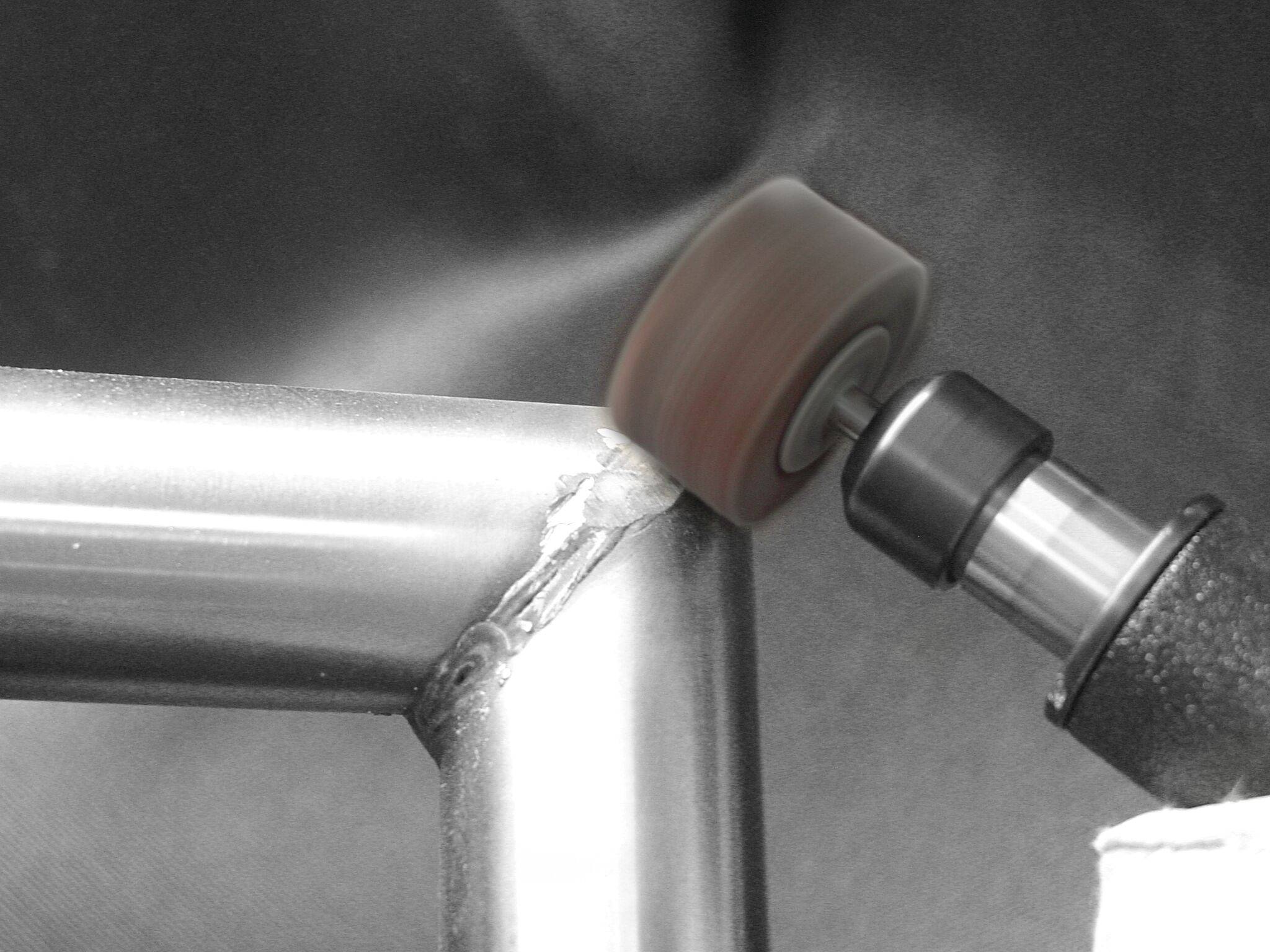 Ein Polierwerkzeug glättet geschweißte Metallröhren an einer Verbindungsstelle und erzeugt eine nahtlose, glänzende Oberfläche.