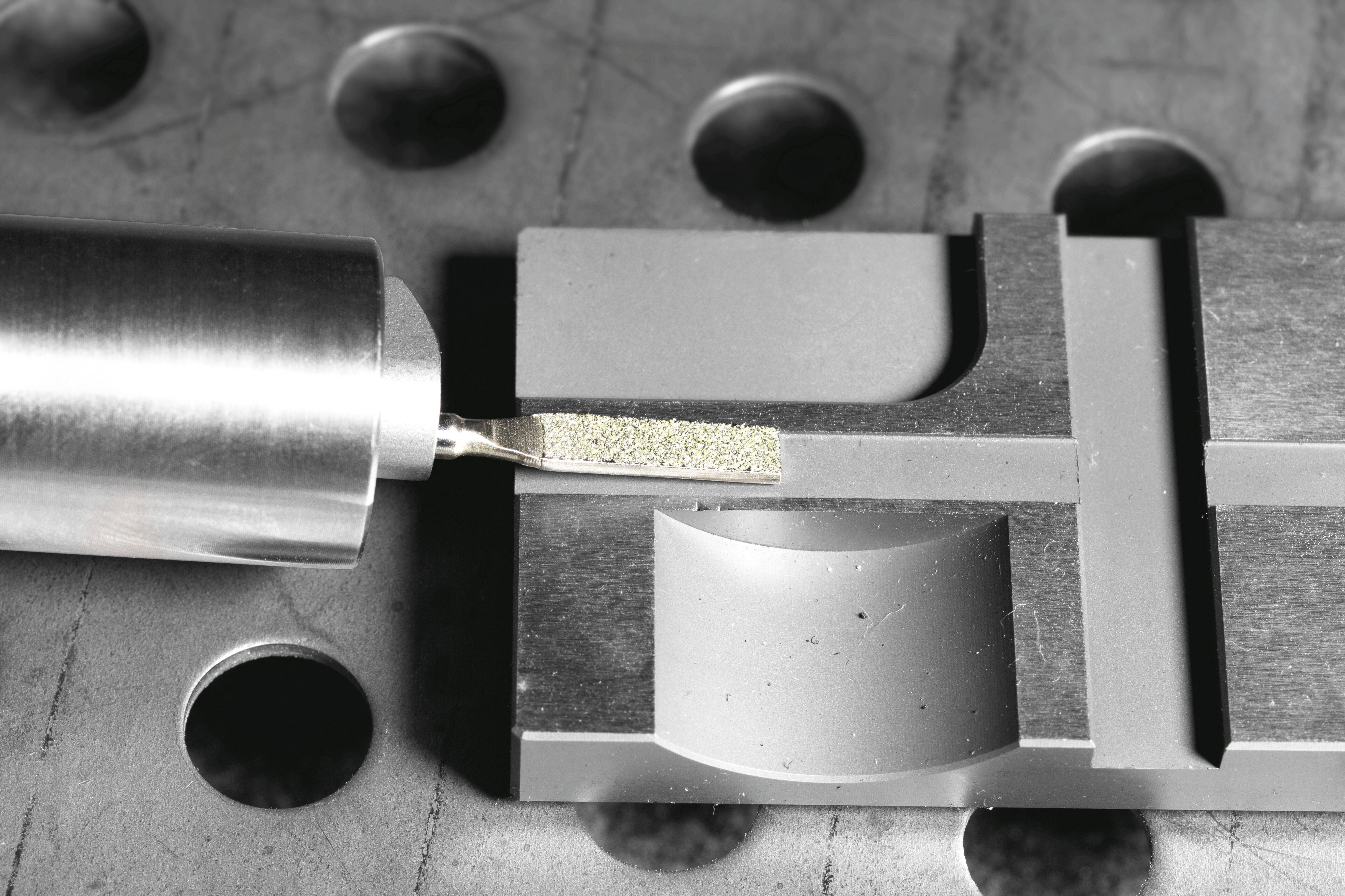 Eine mechanische Komponente auf einer Metalloberfläche, wobei sich ein zylindrisches Werkzeug neben einem rechteckigen Teil befindet, was möglicherweise auf Einstellung oder Analyse hindeutet.