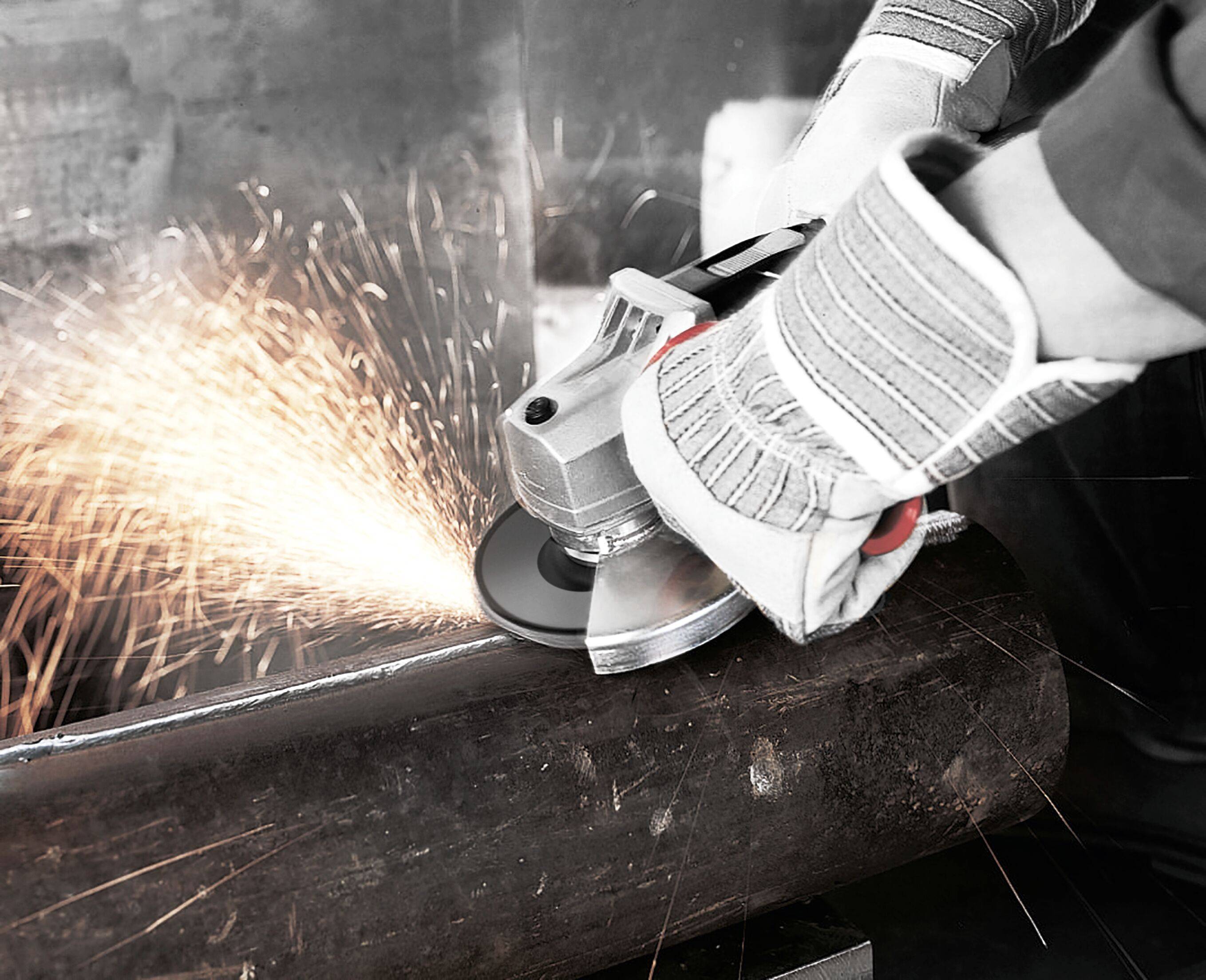 Eine Person bearbeitet eine Metallrohr mit einer Trennscheibe und erzeugt dabei Funken. Es werden Sicherheitshandschuhe getragen, was die Bedeutung von Schutzmaßnahmen bei Metallarbeiten unterstreicht.