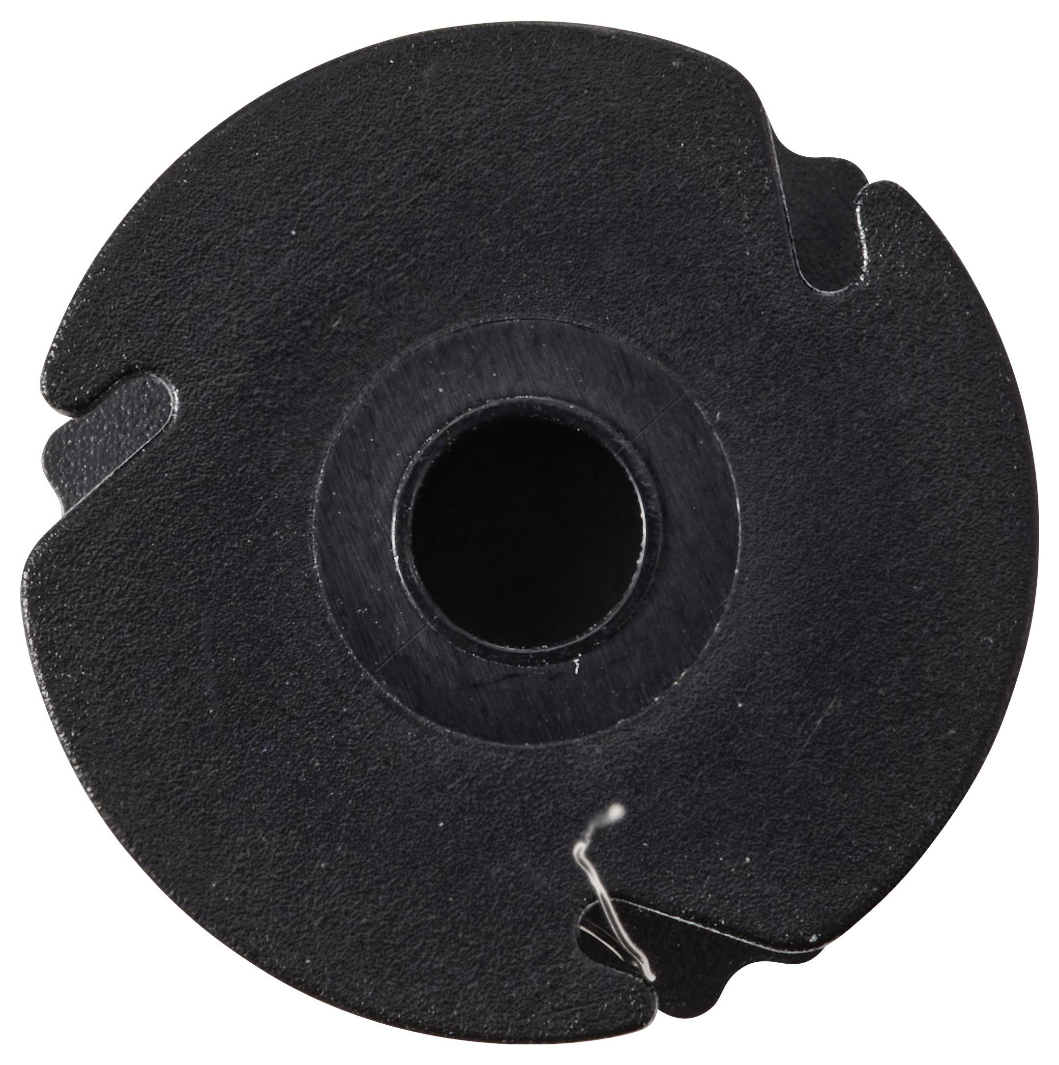 Eine Nahaufnahme eines schwarzen kreisförmigen Objekts mit einem zentralen Loch und kleinen Kerben am Rand, möglicherweise eine Spule oder eine mechanische Komponente.