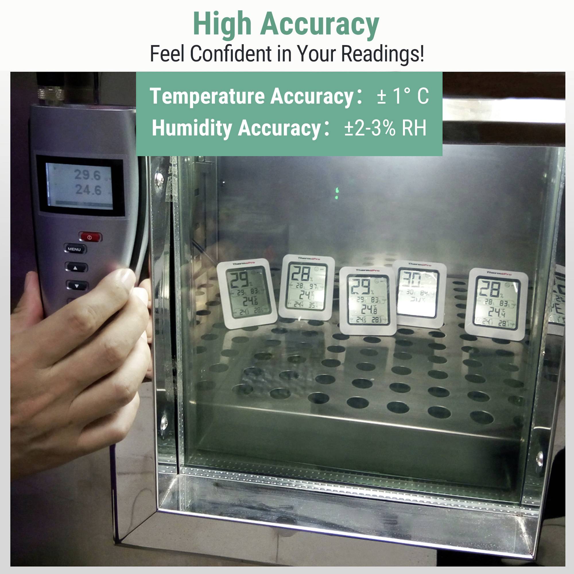 Eine Person verwendet ein Thermometergerät an einer Box mit vier digitalen Thermometern, die ähnliche Temperaturen um 24-29°C anzeigen, gekennzeichnet mit hoher Genauigkeit.