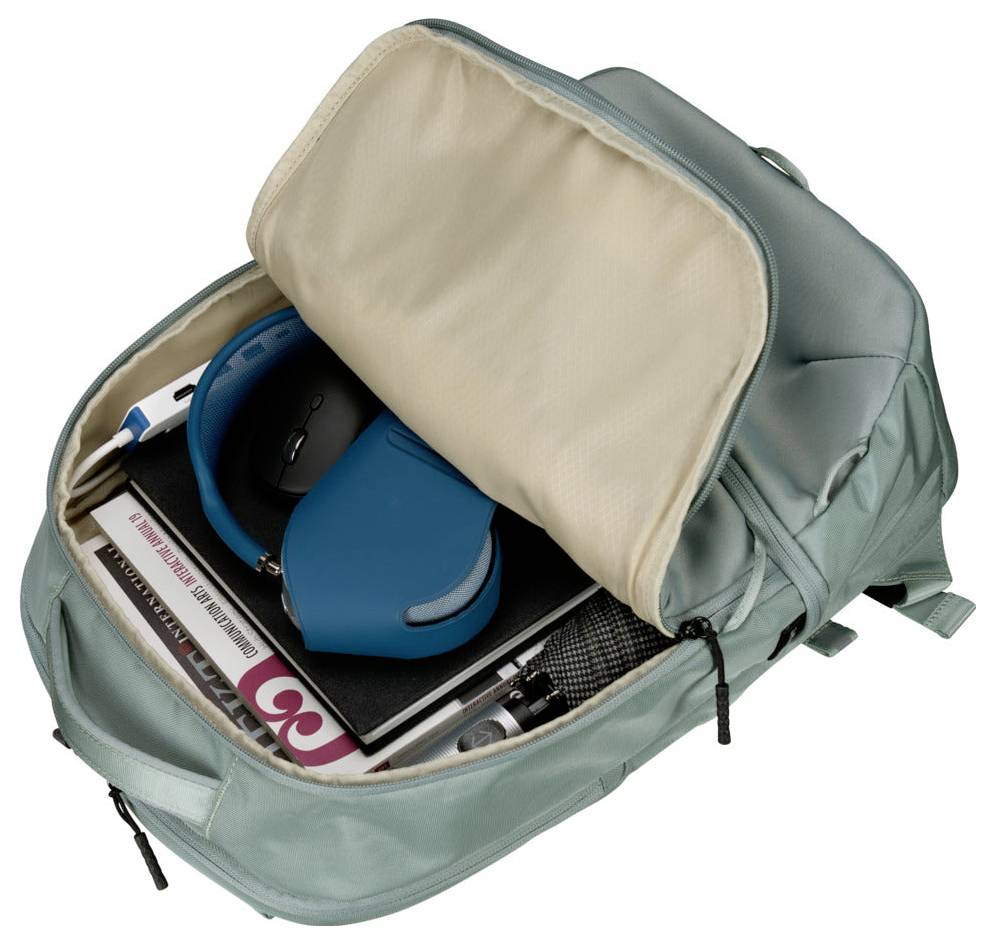 Ein hellblauer Rucksack ist geöffnet und zeigt seinen Inhalt: eine gefaltete Zeitschrift, ein blaues drahtloses Kopfhörer, einen Stift, ein Buch und eine Wasserflasche.