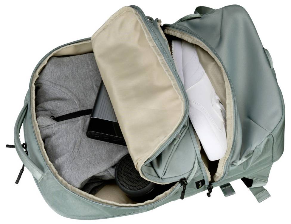 Offener hellturkiser Rucksack mit sichtbaren Inhalten, darunter ein grauer Hoodie, weiße Schuhe, ein schwarzer Lautsprecher und ein schwarzes zylindrisches Item.