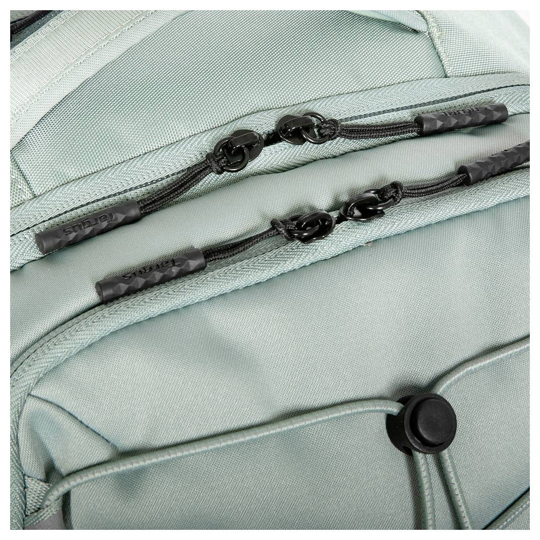 Nahaufnahme von Reißverschlüssen und Trägern eines hellgrünen Rucksacks, die Details des Gewebes und der Designelemente zeigen.