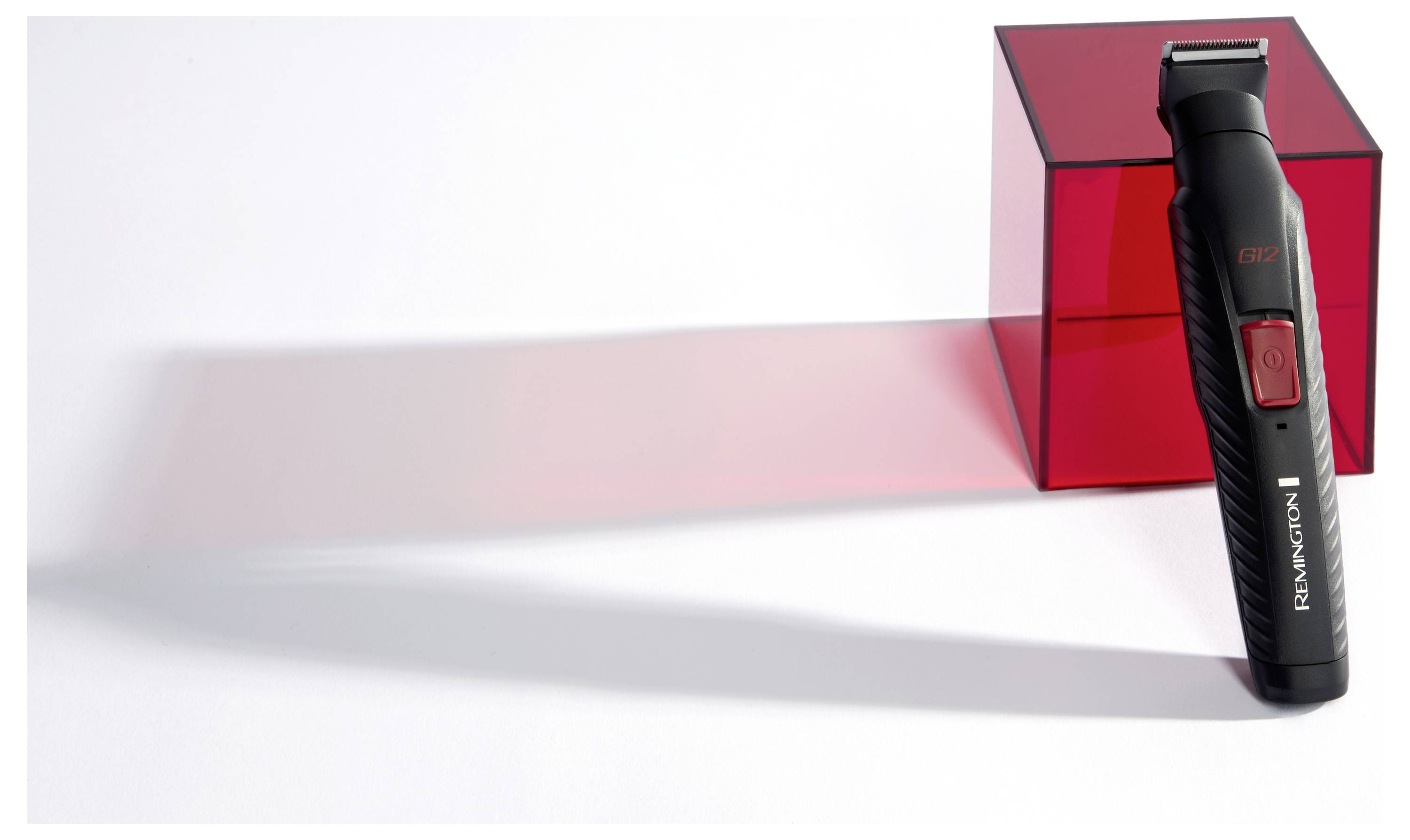 Ein schwarzer und roter Remington Elektrorasierer steht aufrecht neben einem durchsichtigen roten Würfel und wirft einen passenden Schatten auf die Oberfläche.