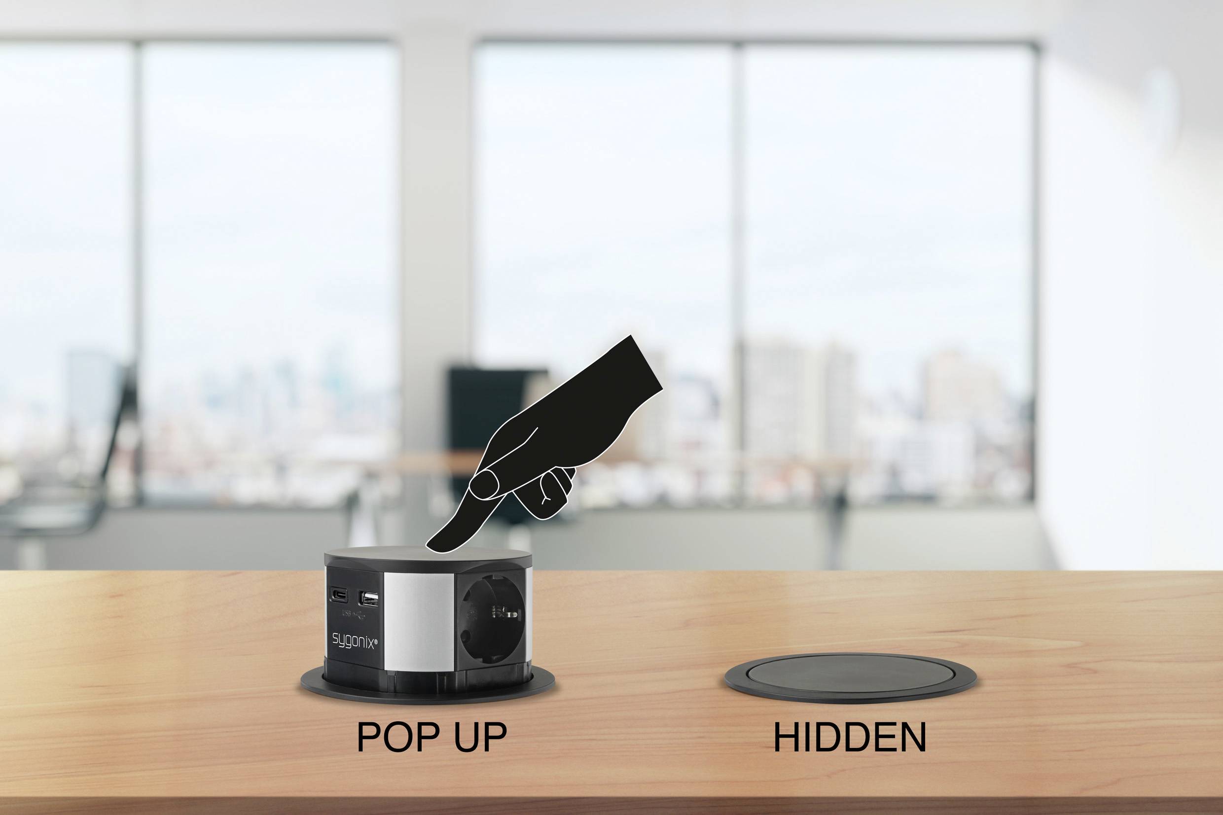 Eine Hand drückt eine Pop-up-Steckdose auf einem Schreibtisch, mit der Beschriftung 