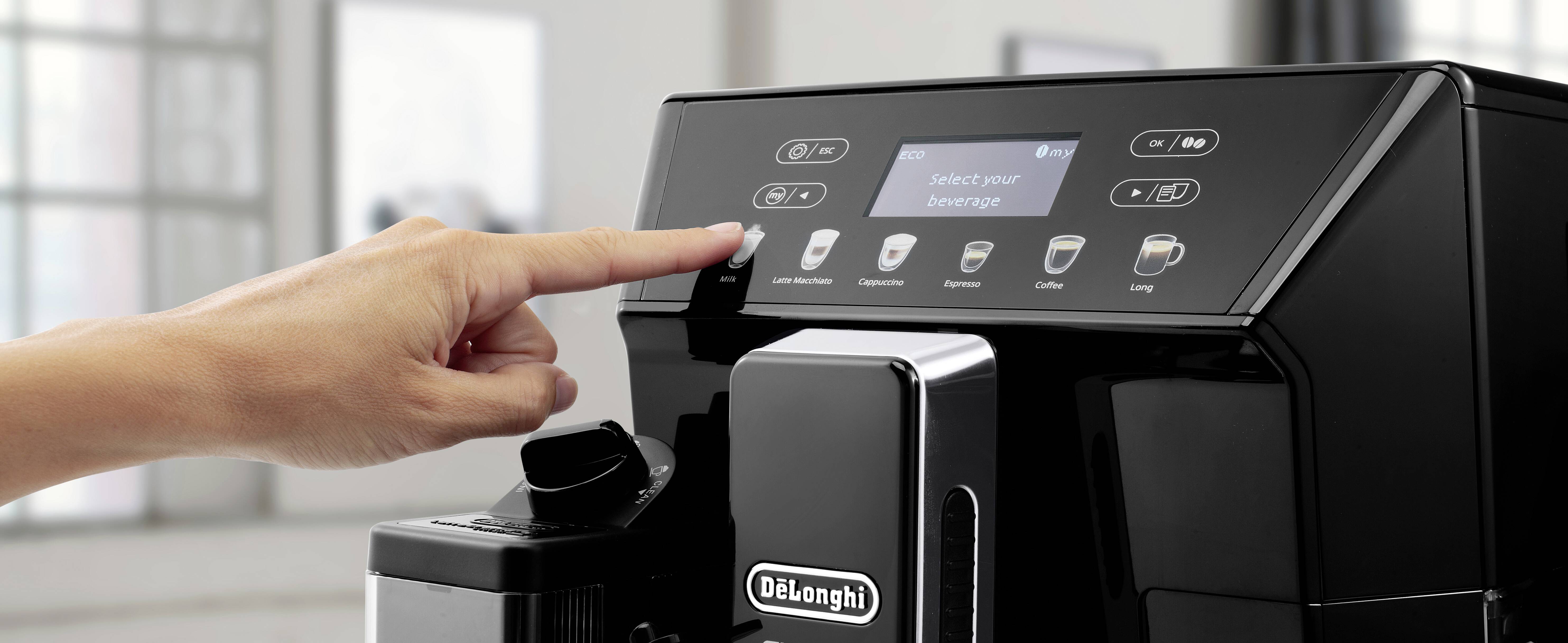 Eine Person drückt eine Taste auf dem Bildschirm einer De'Longhi Kaffeemaschine, auf dem 