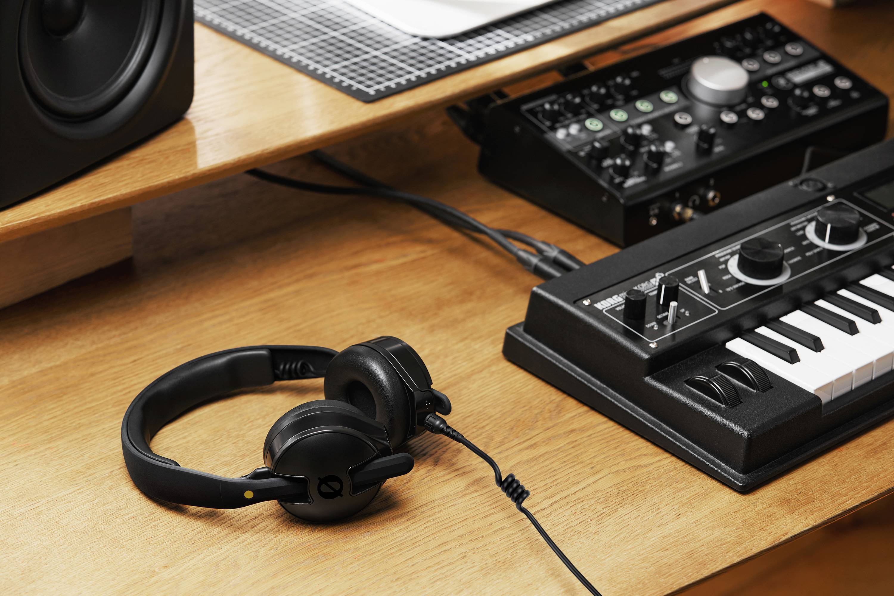 Ein hölzerner Schreibtisch trägt eine kleine Tastatur, eine Audioschnittstelle und Kopfhörer und deutet auf einen Heimmusik-Produktionsarbeitsplatz hin.