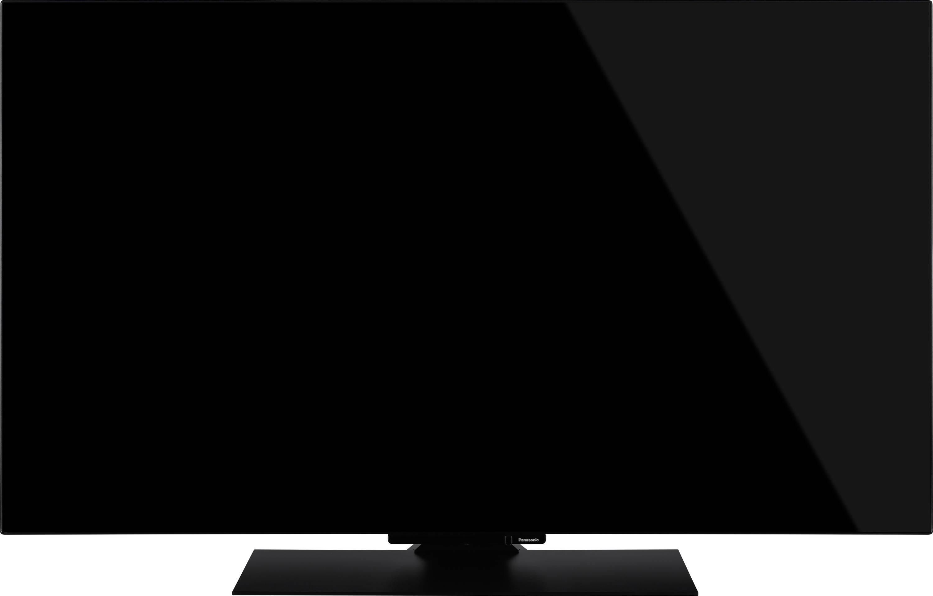 Ein Flachbildschirm-Fernseher mit einem schwarzen, glänzenden Bildschirm, der auf einem rechteckigen Ständer montiert ist. Der Bildschirm ist ausgeschaltet und reflektiert nur minimales Licht.